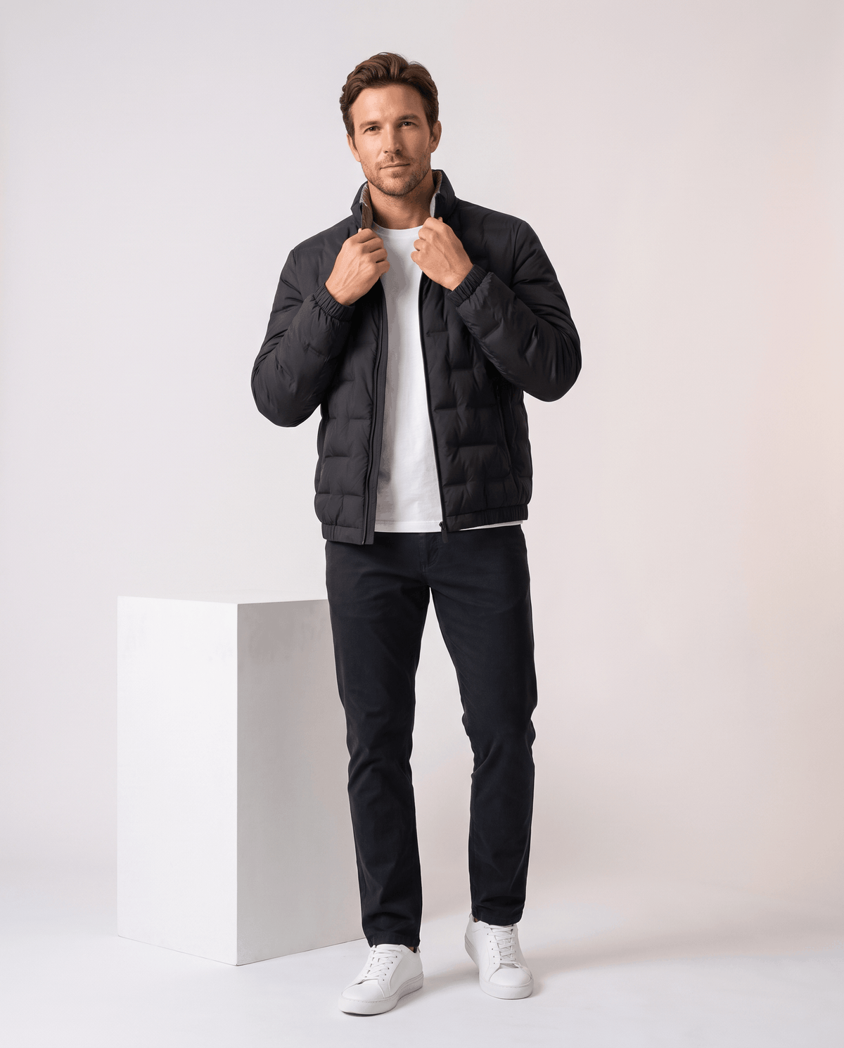 Man in the black Sutton quilted down jacket holding the stand collar, beige lining visible
