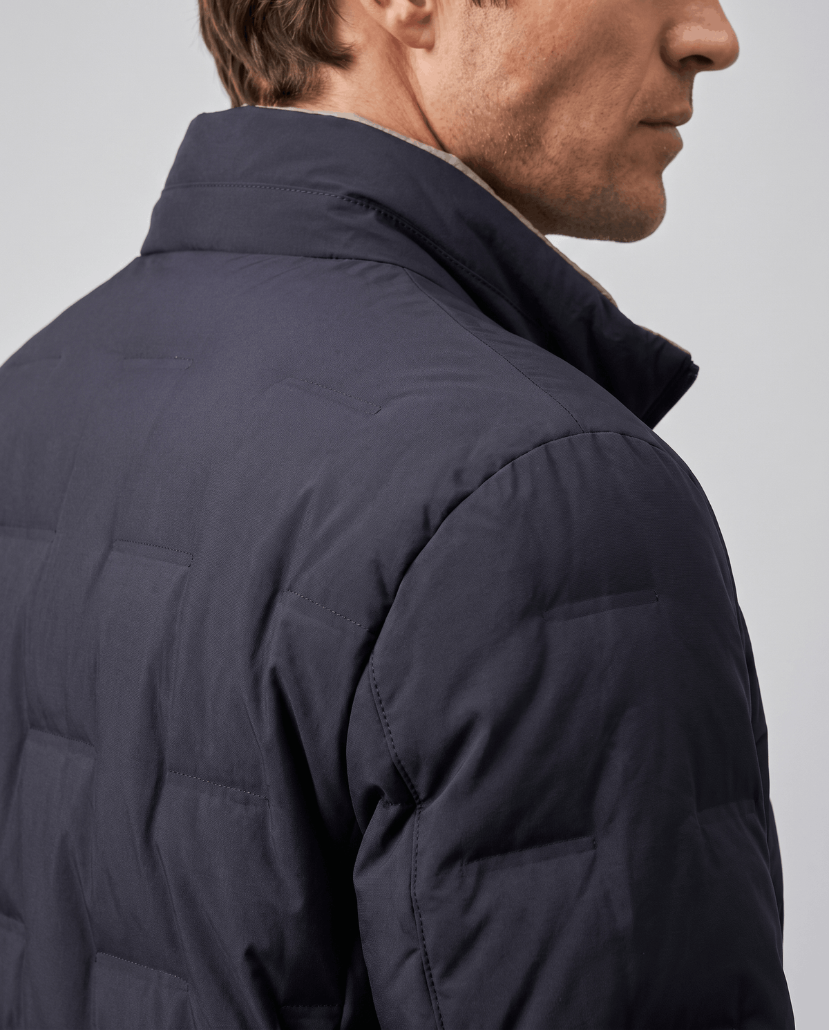Shoulder detail of the blue Sutton quilted down jacket showing square block quilting