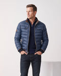 Man wearing navy quilted puffer bomber jacket with tan leather-look collar trim