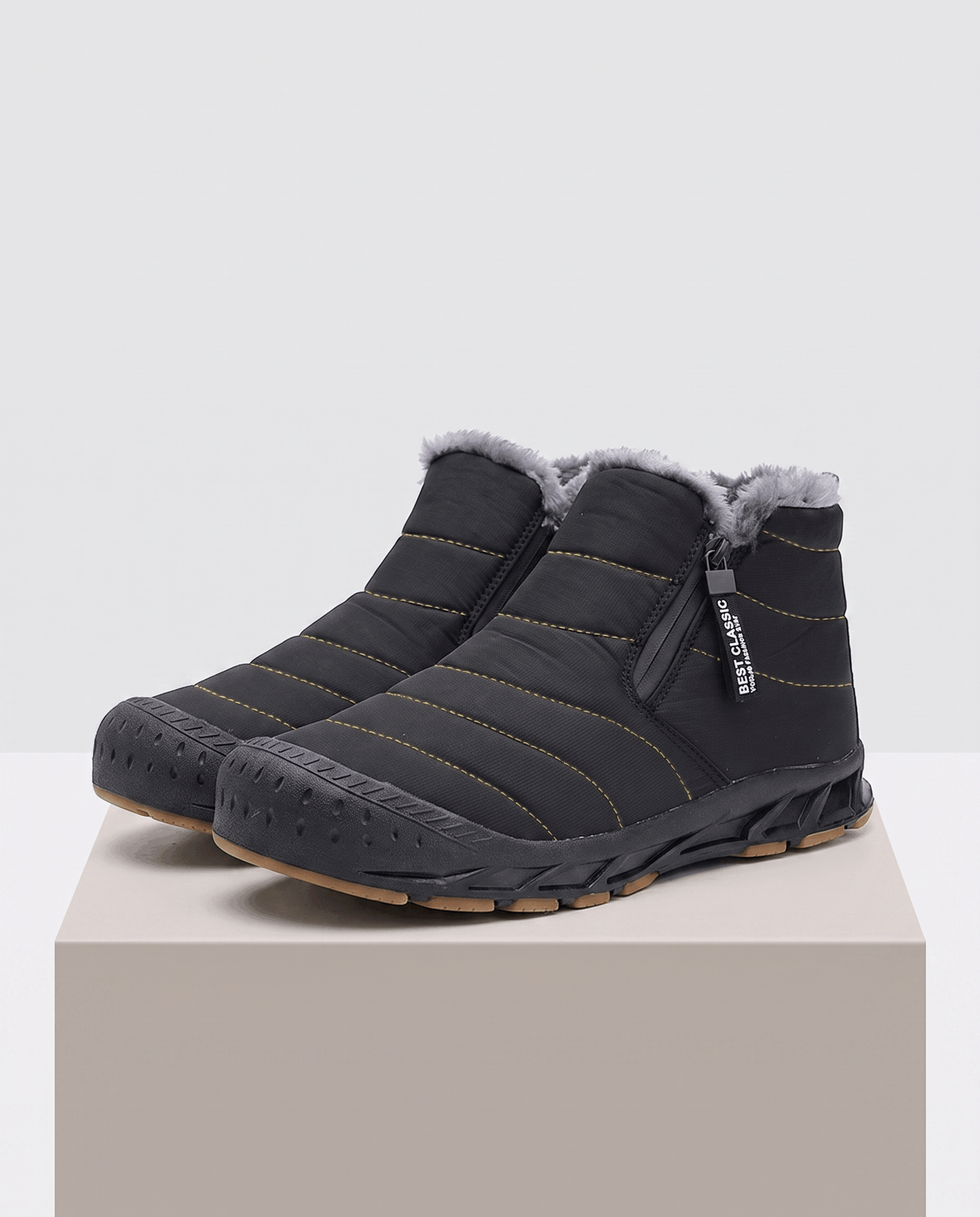 Black insulated ankle boots displayed on a pedestal.