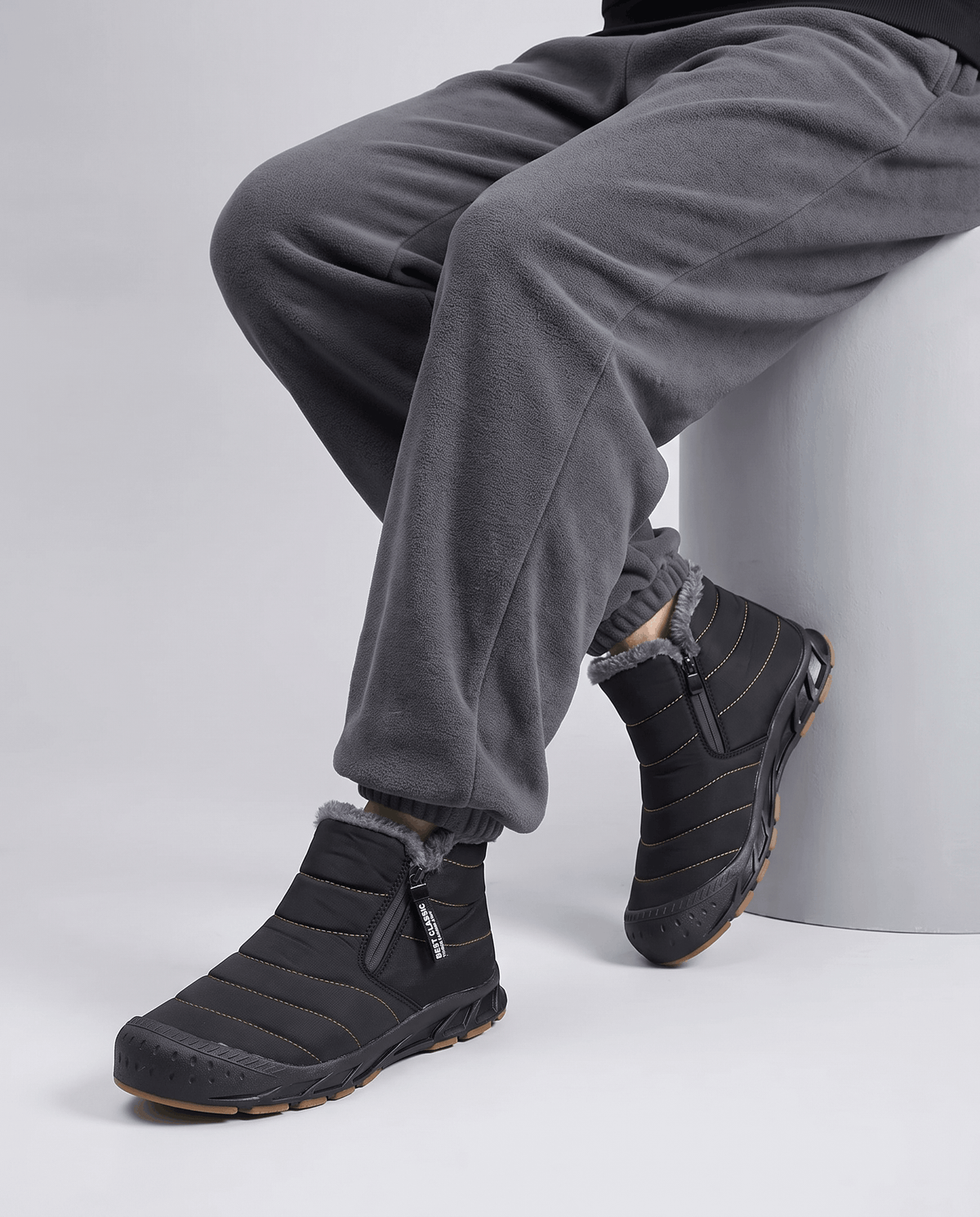 Man wearing black insulated boots with gray pants.