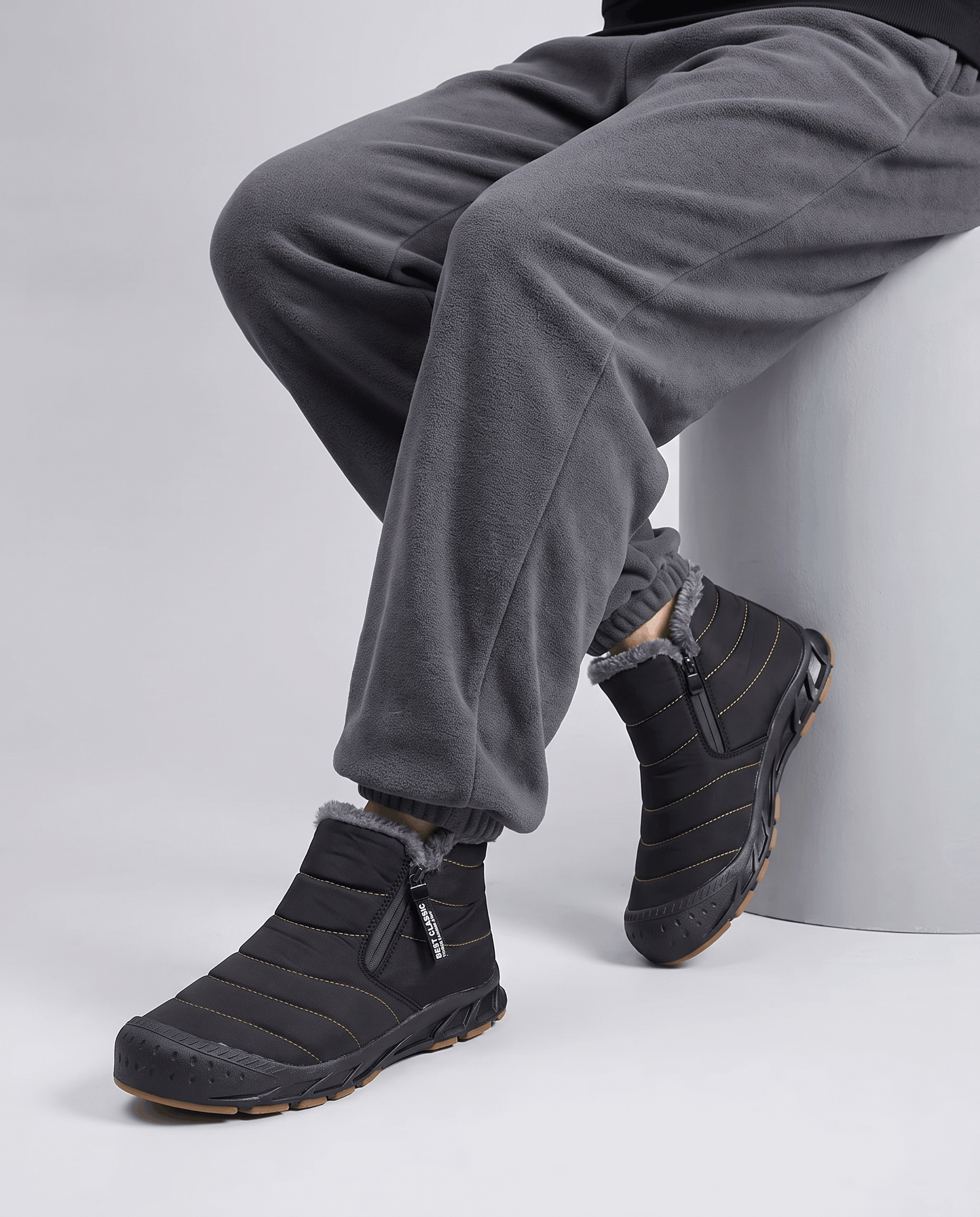 Man wearing black insulated boots with gray pants.