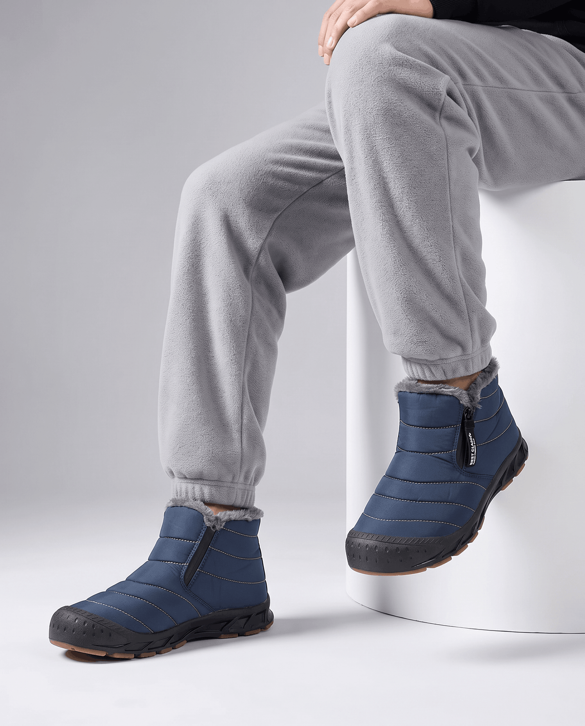 Person wearing blue insulated boots with gray pants.