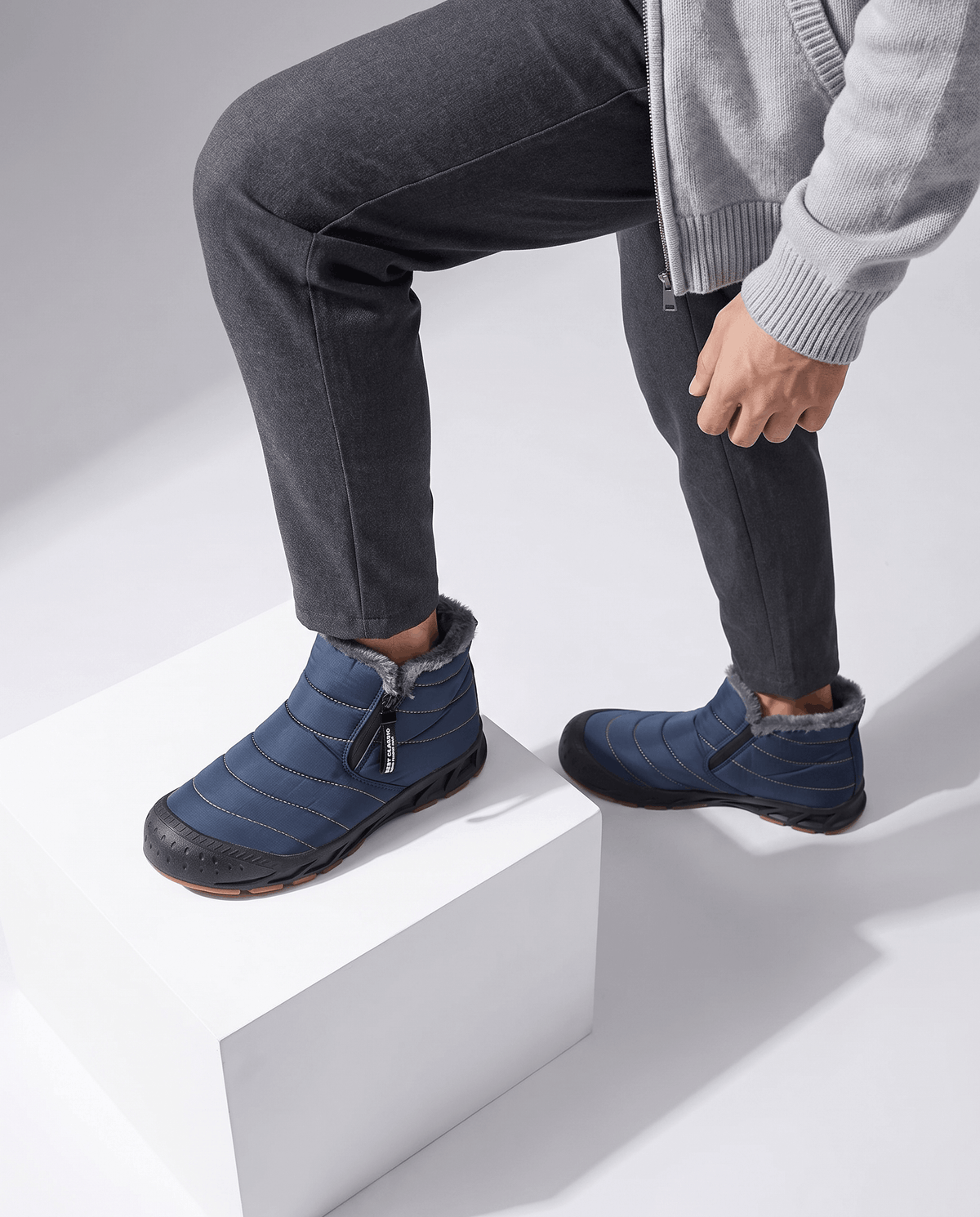 Person wearing blue insulated boots while standing on white steps.