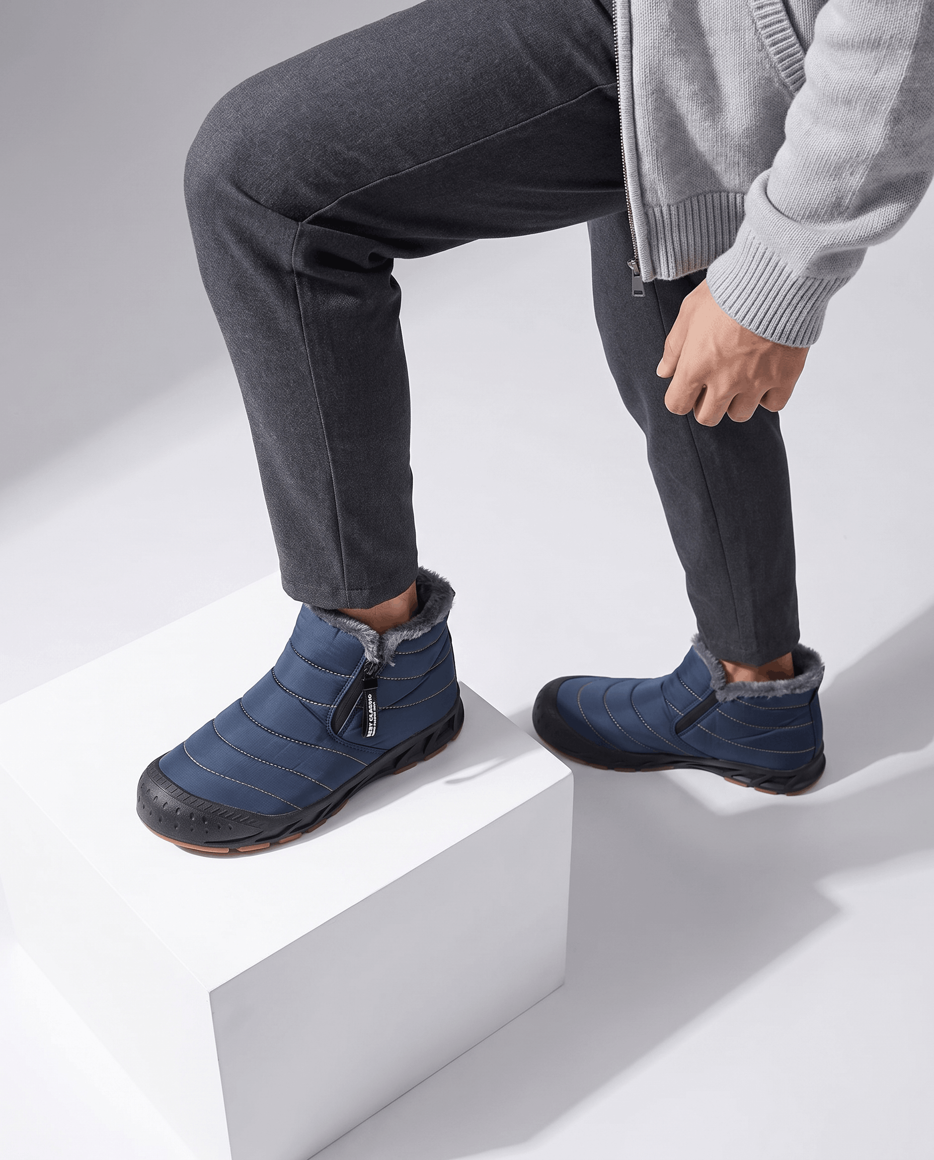 Person wearing blue insulated boots while standing on white steps.