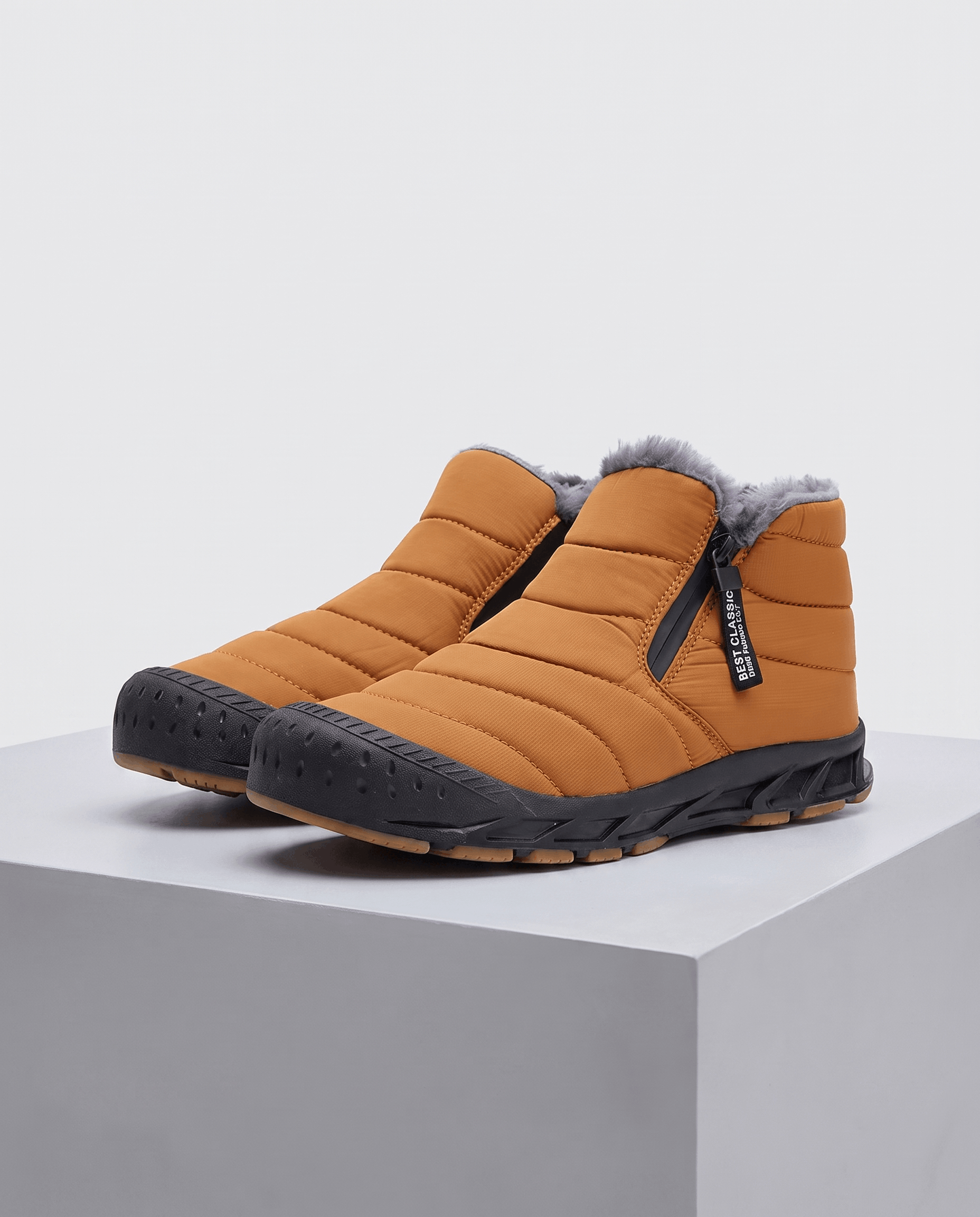 Pair of orange insulated ankle boots displayed on a pedestal.