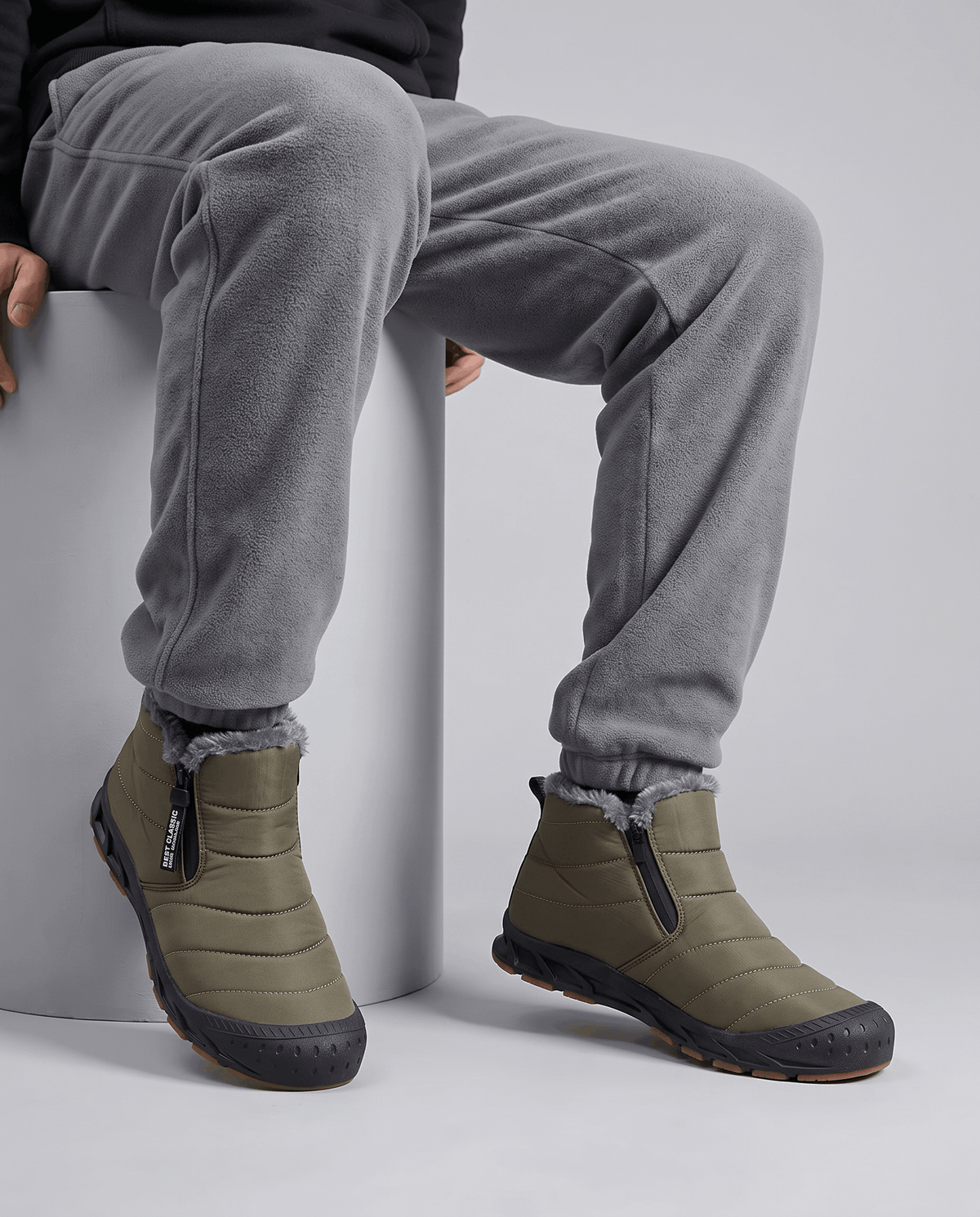 Person wearing green insulated boots with gray pants.