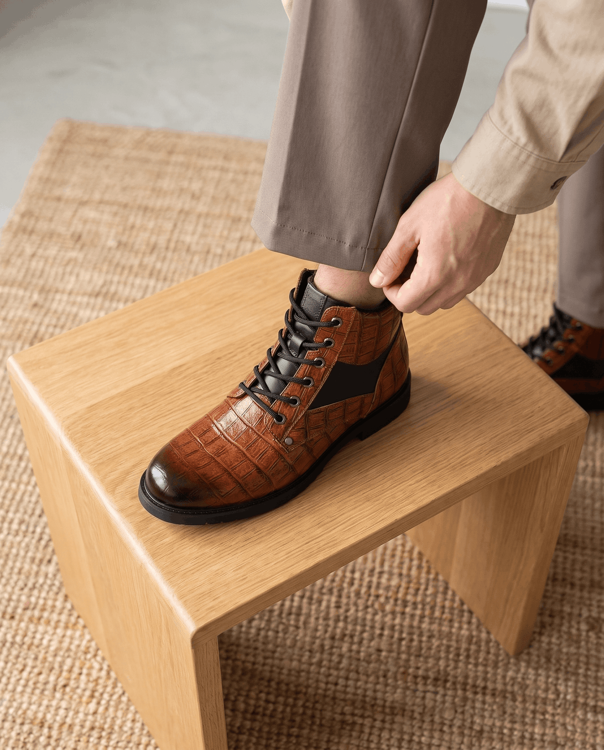 Brown embossed reptile leather ankle boots with black panel insets, metal eyelets, and a chunky lug outsole.