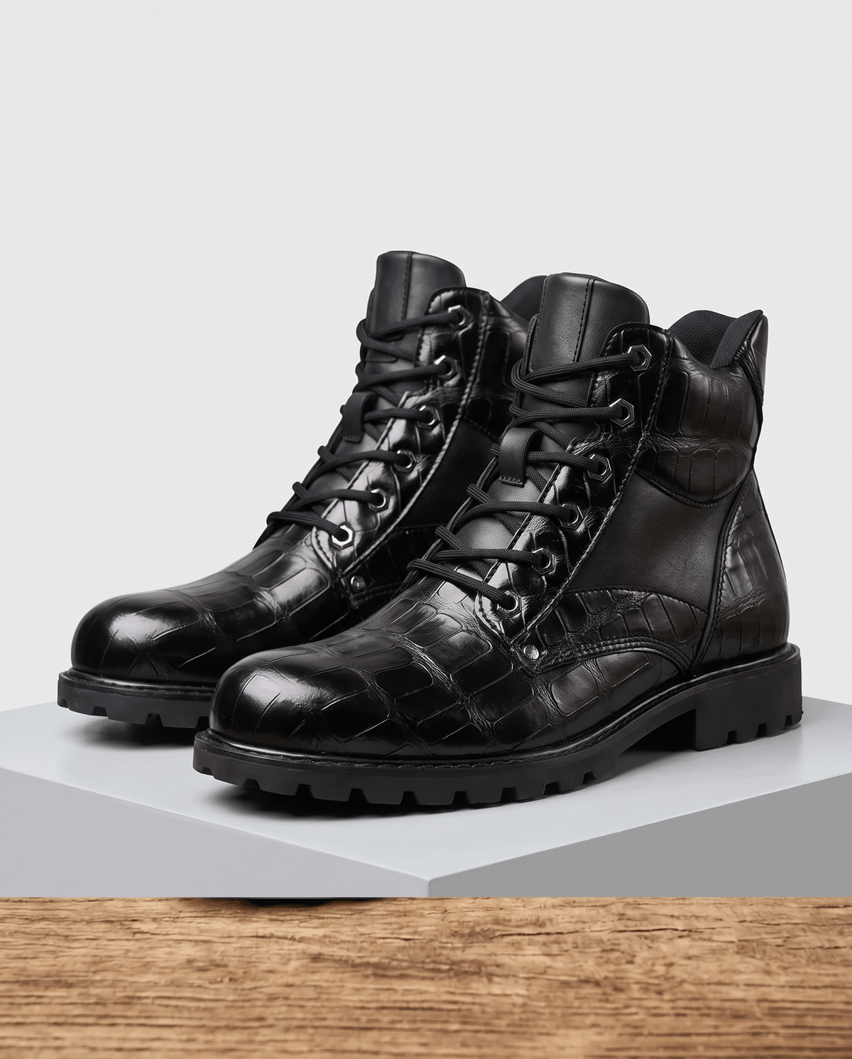 Black embossed reptile-grain leather ankle boots with polished metal eyelets, lace-up closure, and a chunky lug outsole.