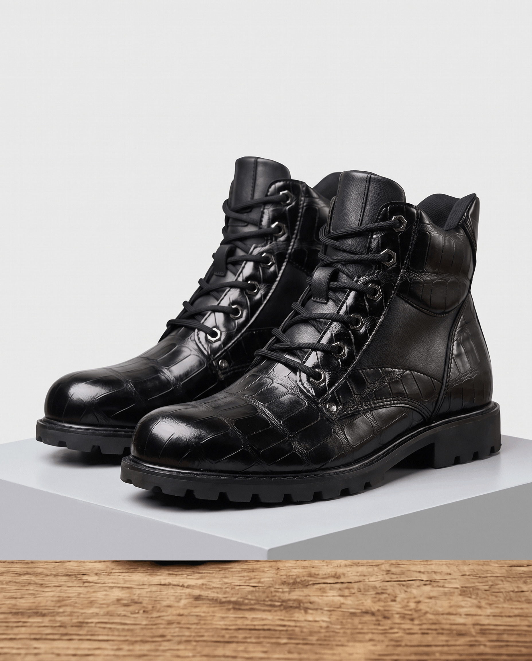 Black embossed reptile-grain leather ankle boots with polished metal eyelets, lace-up closure, and a chunky lug outsole.