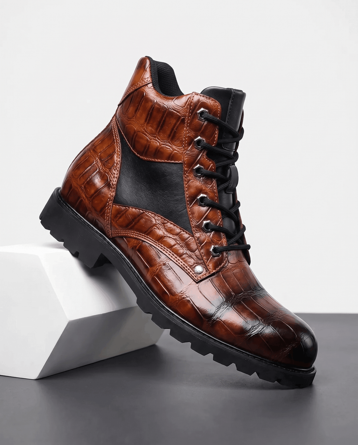 Dark brown embossed reptile-grain leather ankle boots with black panel insets, metal eyelets, and a chunky lug outsole.