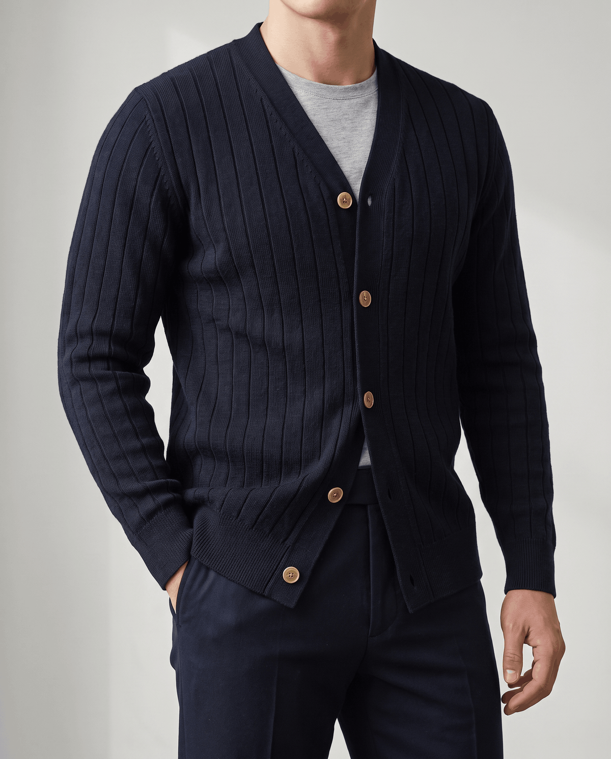 Close-up of the navy cardigan showing tan buttons and a hand in the trouser pocket