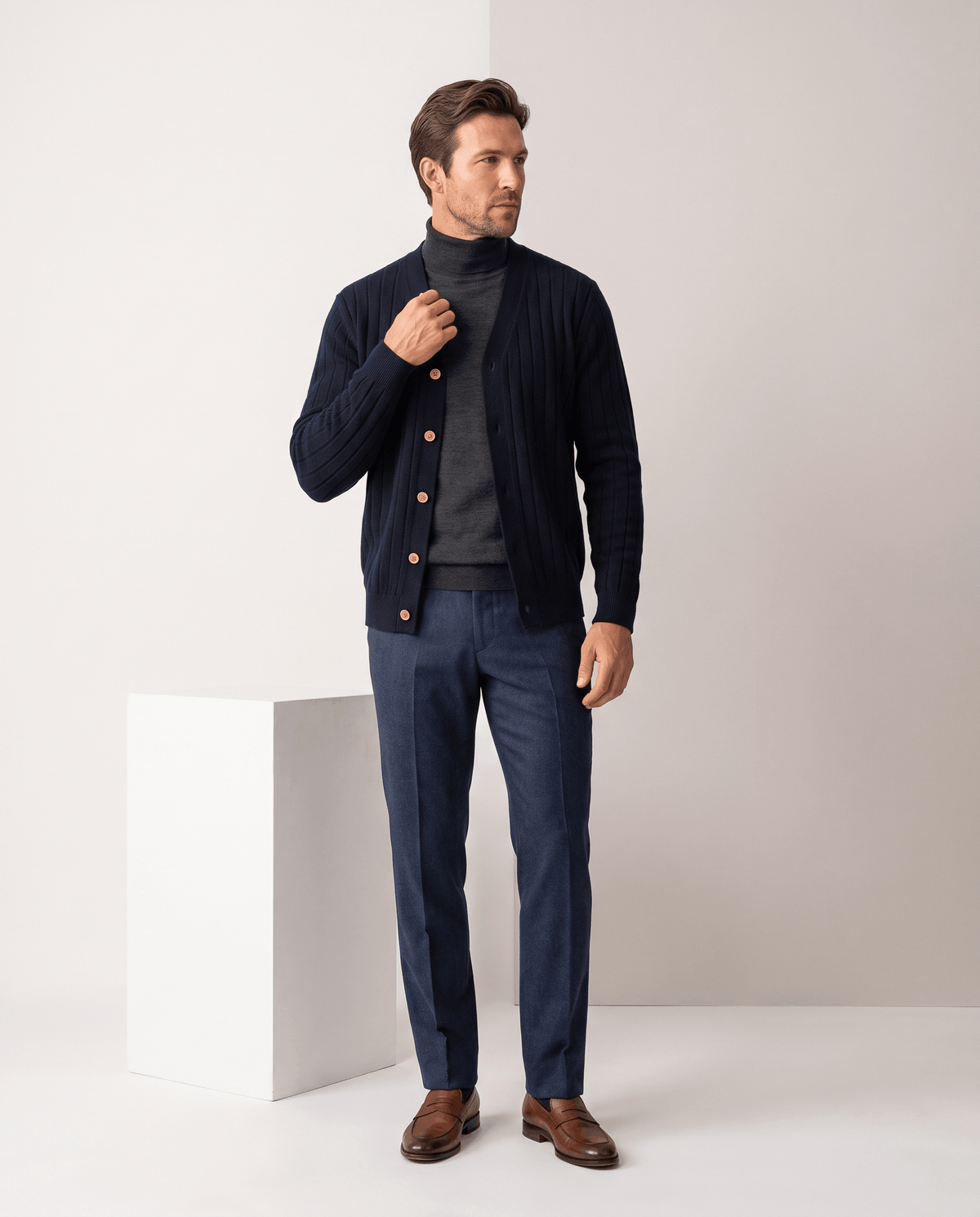 Full-length view of the navy cardigan with a black turtleneck, jeans and brown shoes