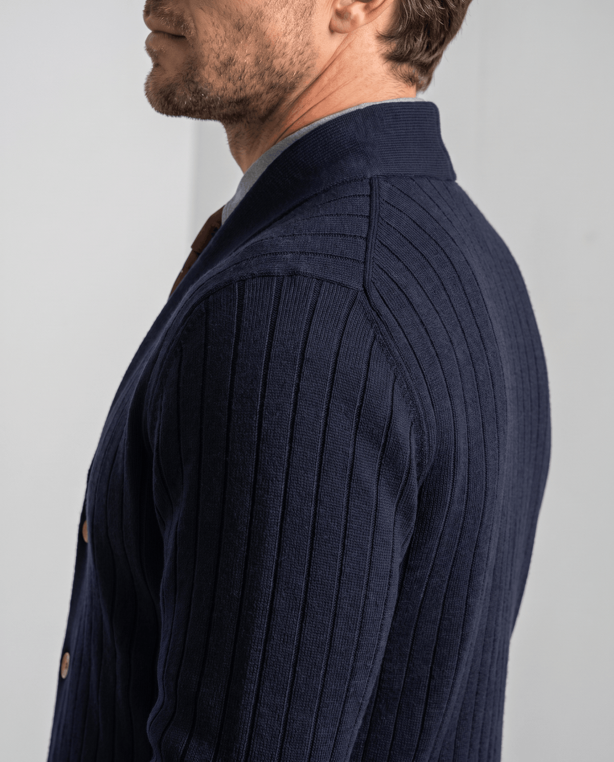 Side profile of the navy knit showing vertical ribs across the shoulder