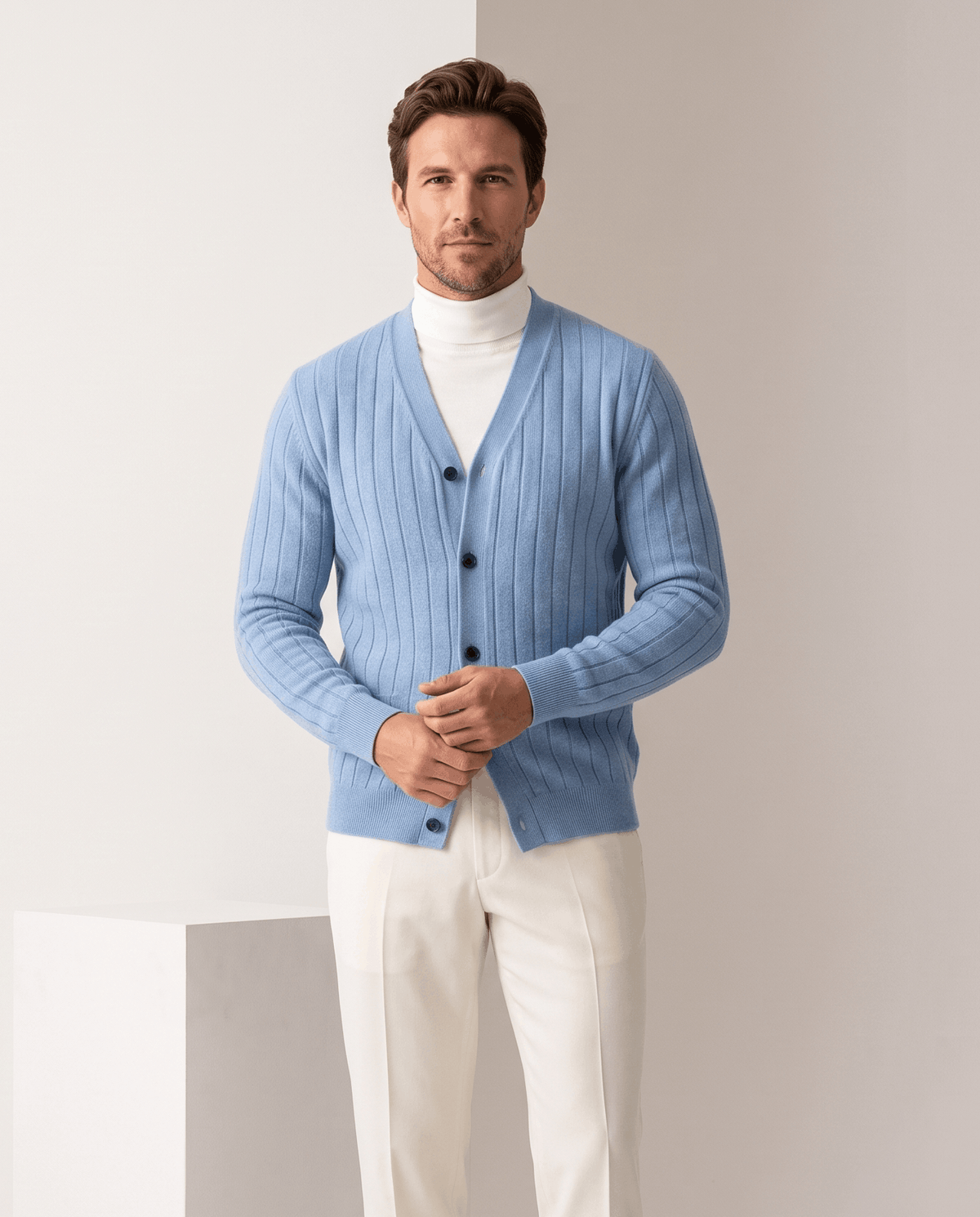 Man wearing a sky blue ribbed knit V-neck cardigan sweater with cream trousers