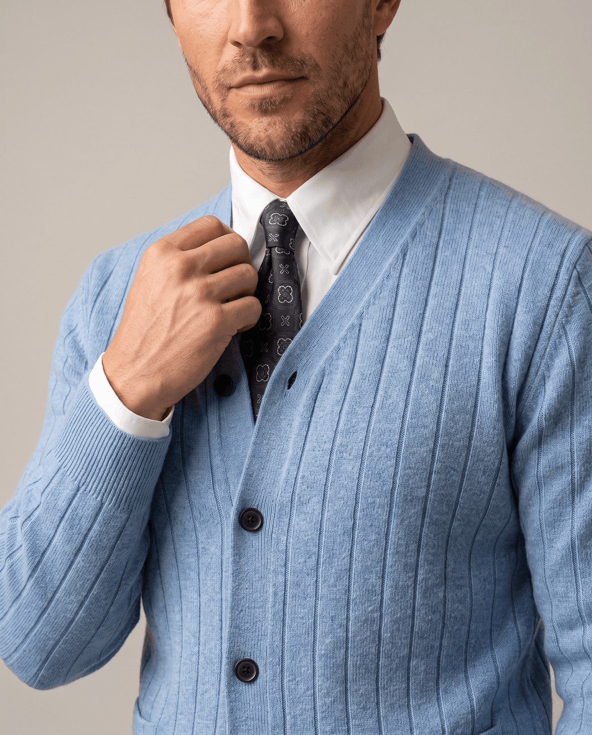 Close-up of the sky blue ribbed cardigan buttoned over a white shirt and dark tie