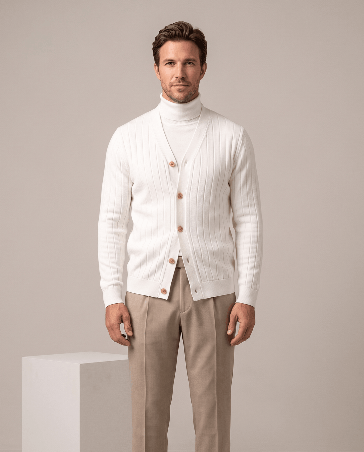 White ribbed cardigan buttoned over a white turtleneck with khaki trousers