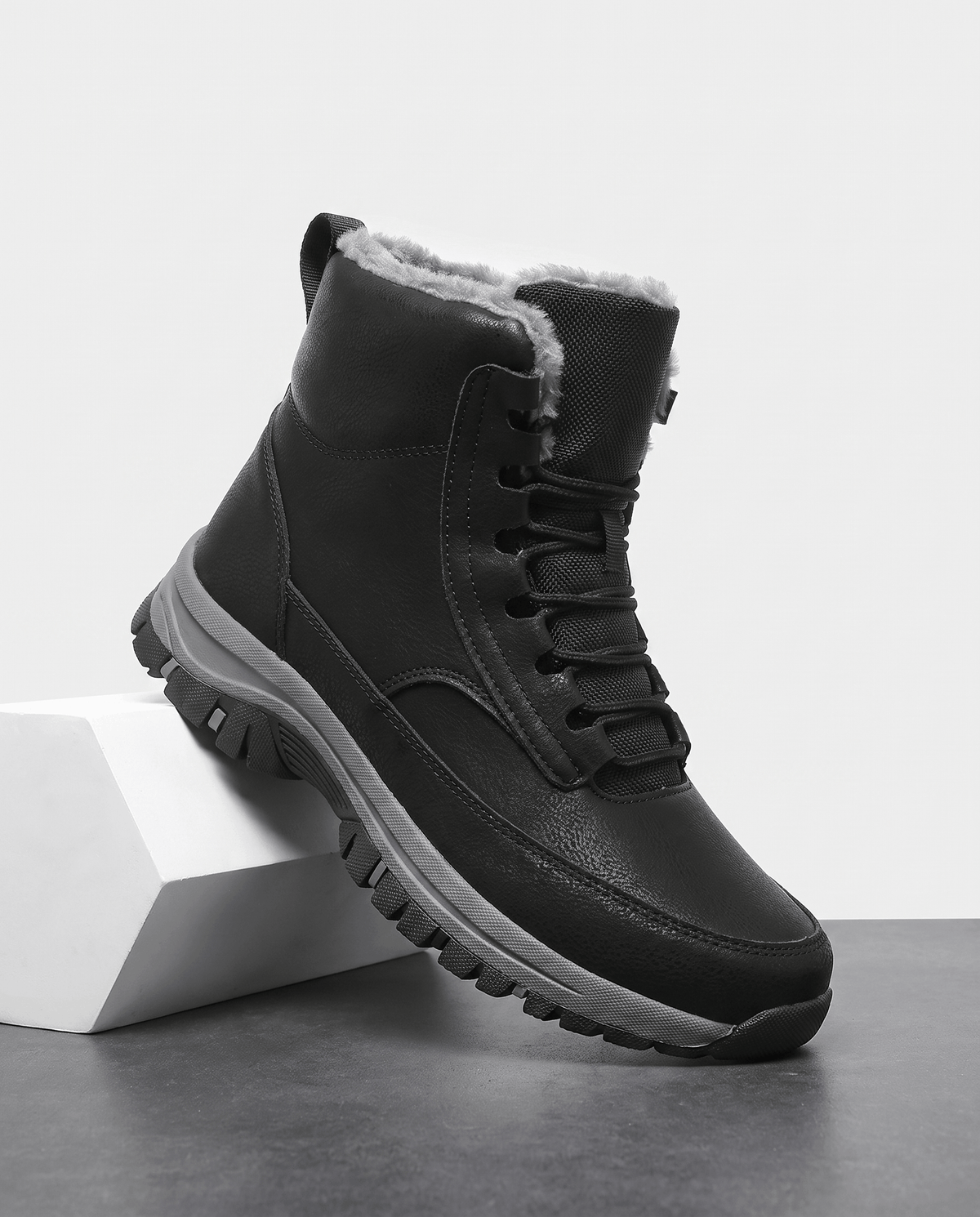 Black insulated lace-up winter boot displayed on a white pedestal.