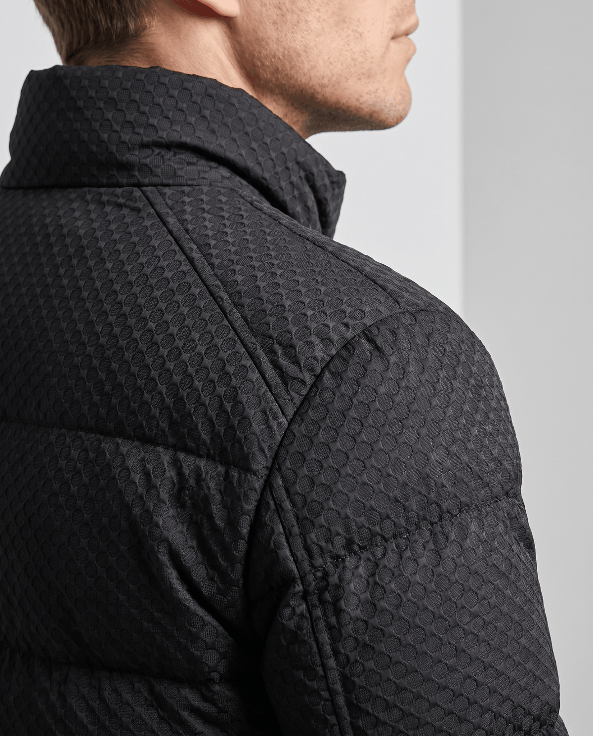 Close-up of the embossed texture on a black puffer shoulder and collar