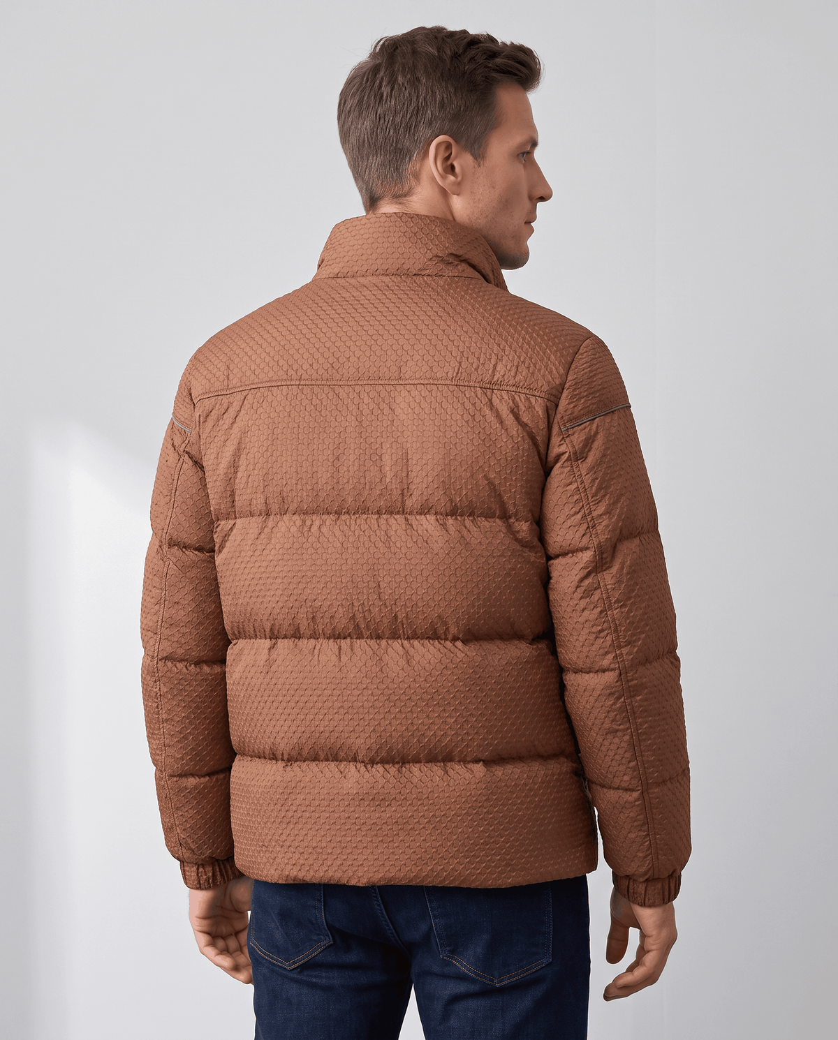 Back view of a caramel brown puffer showing horizontal padded channels and stand collar