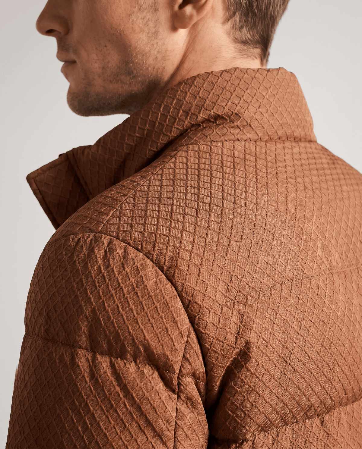 Close-up of the embossed brown shell texture across a caramel puffer shoulder