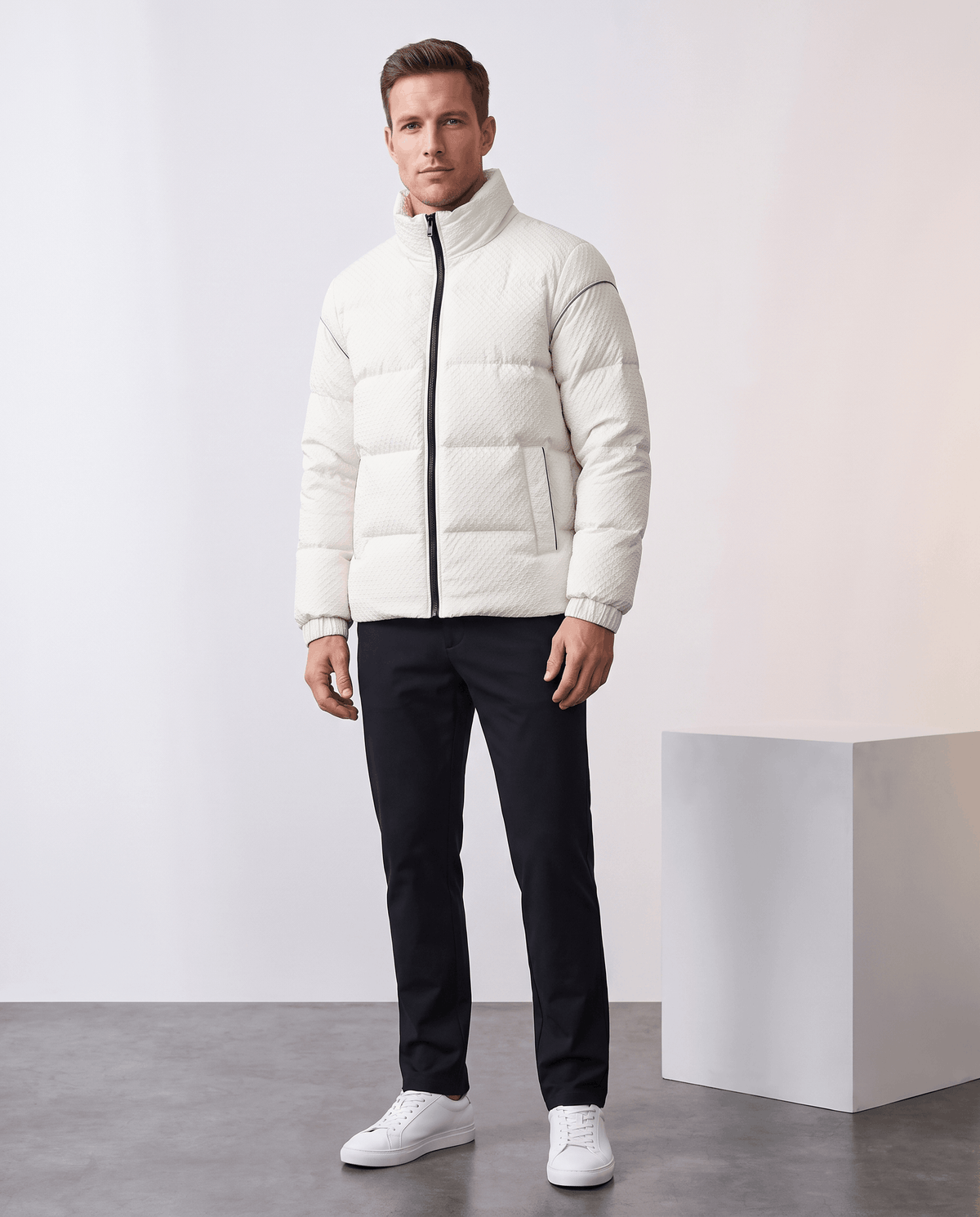 Full-length white puffer styled with navy trousers and white low-top sneakers