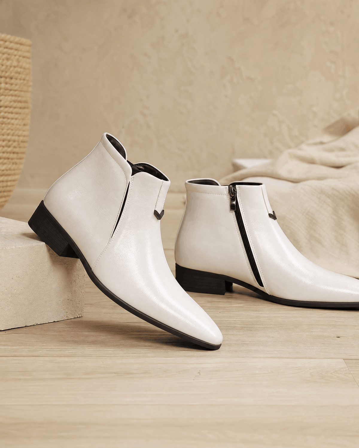 White polished grain ankle boots with a pointed toe, side zip closure, and a low black block heel on a neutral surface.
