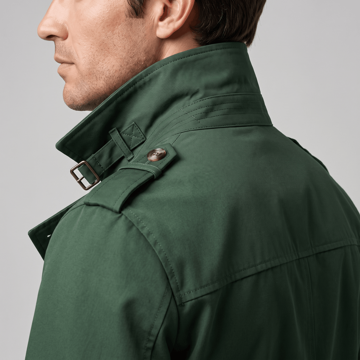 Close-up of the dark green trench coat showing the raised collar and shoulder epaulette.