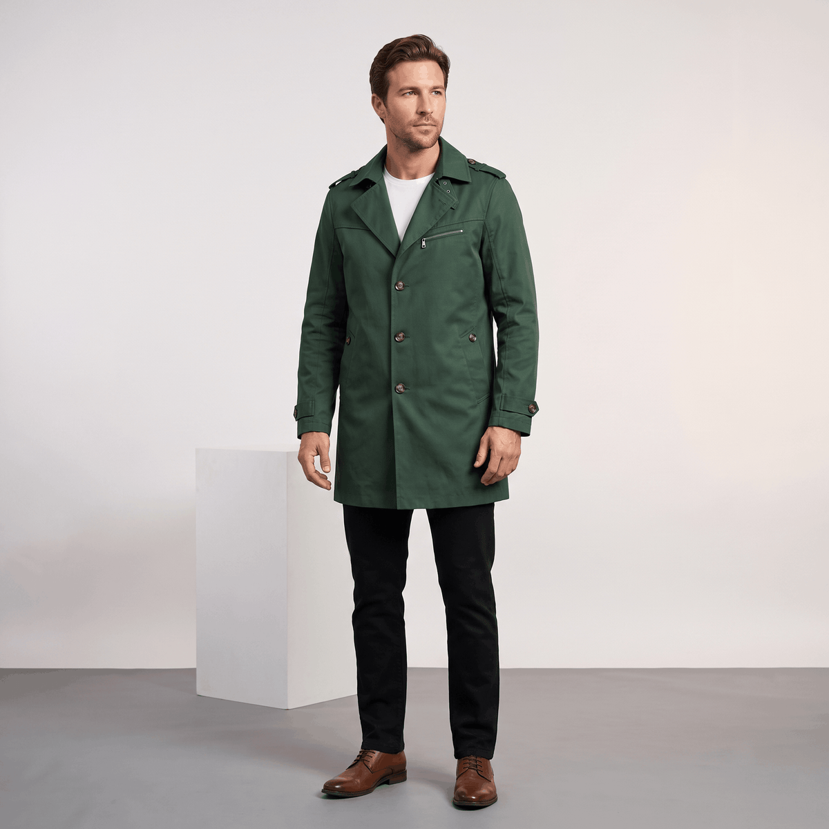 Man wearing a dark green men's trench coat with button closure and front pockets.