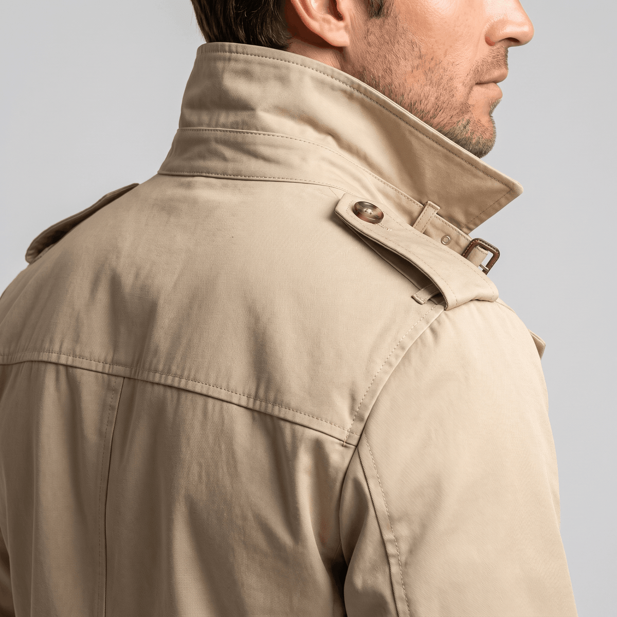 Close-up back view of a beige trench coat showing the raised collar and shoulder detail.