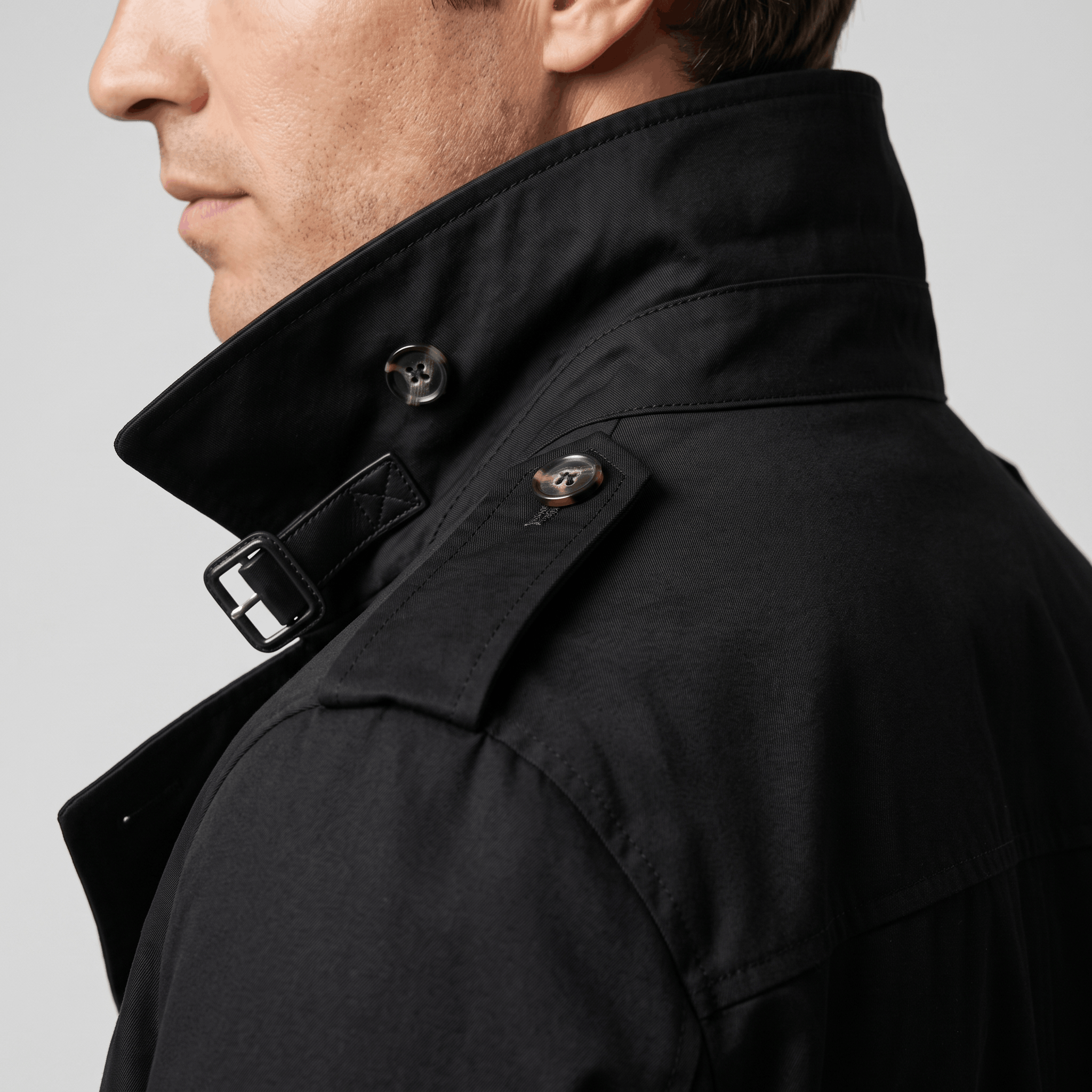 Close-up side view of a black trench coat with a raised collar.