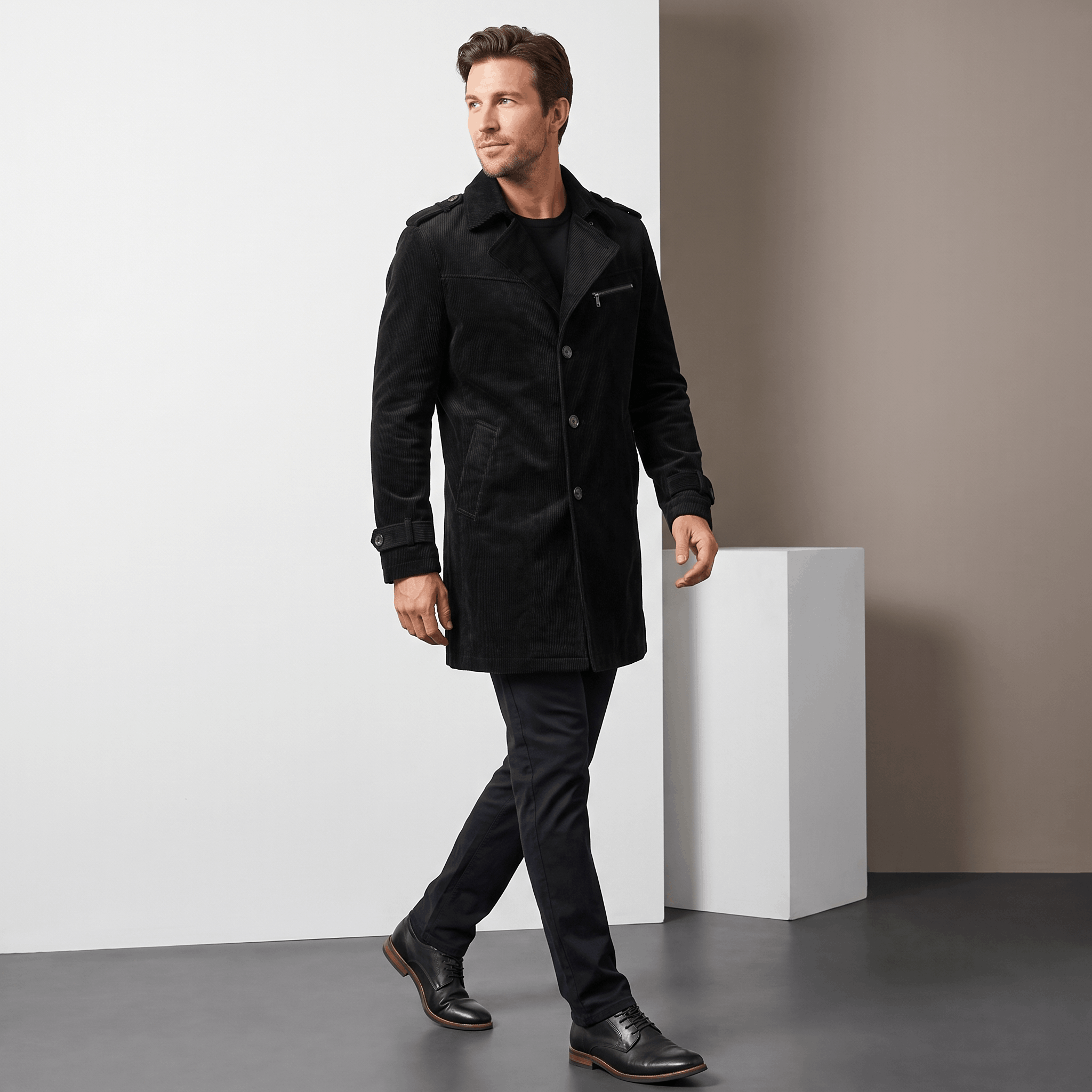 Man wearing a black trench coat in a full-body studio setting.