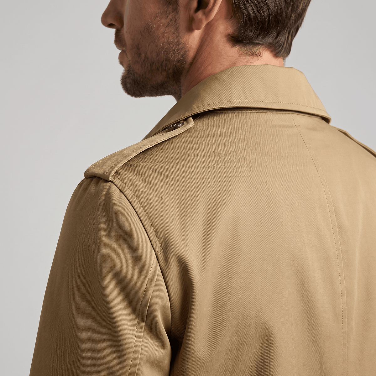 Back view of a beige trench coat showing the collar and shoulder details.