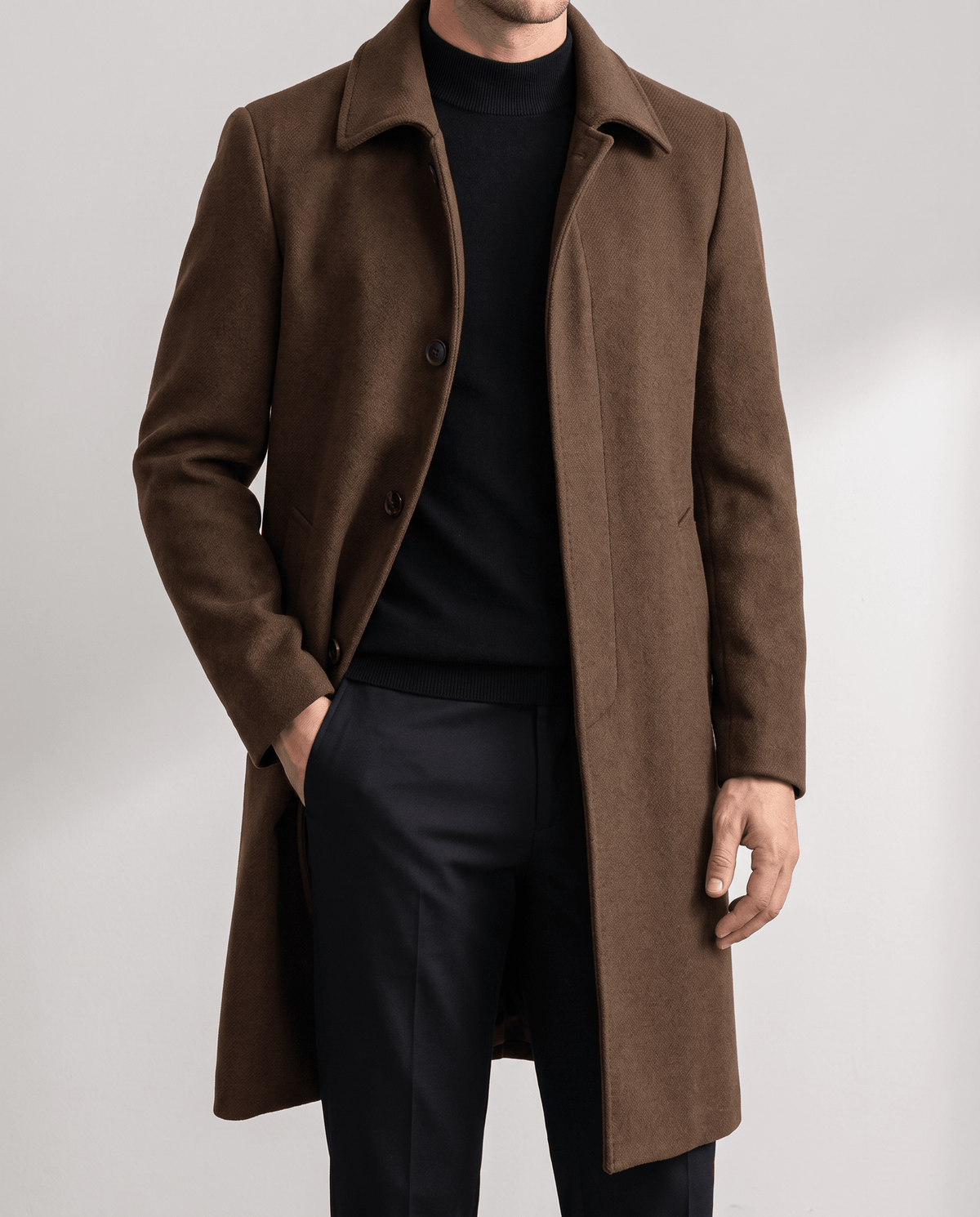 Brown overcoat worn open over a black turtleneck, with a hand in the pocket