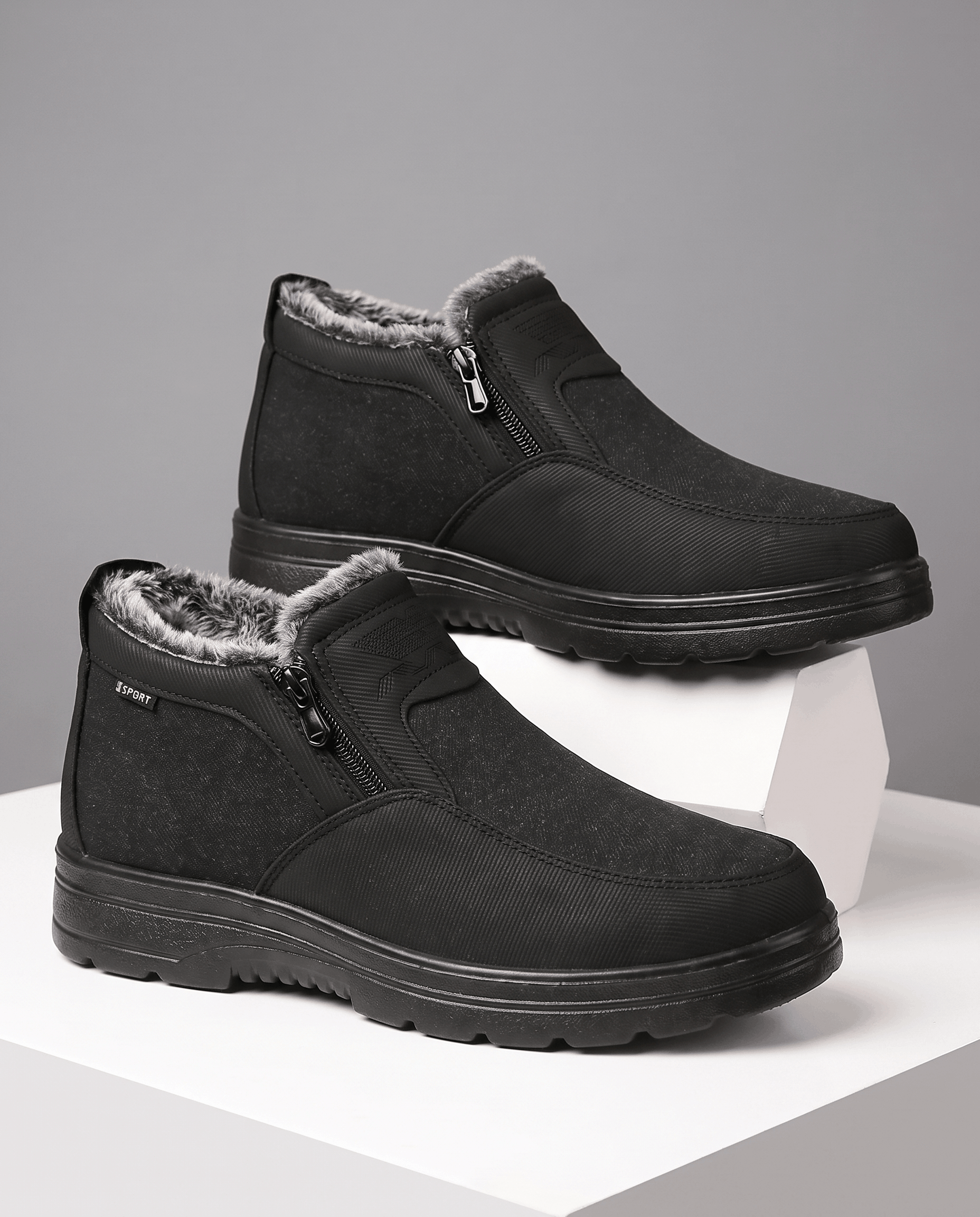 Pair of black fleece-lined ankle boots displayed on white blocks.