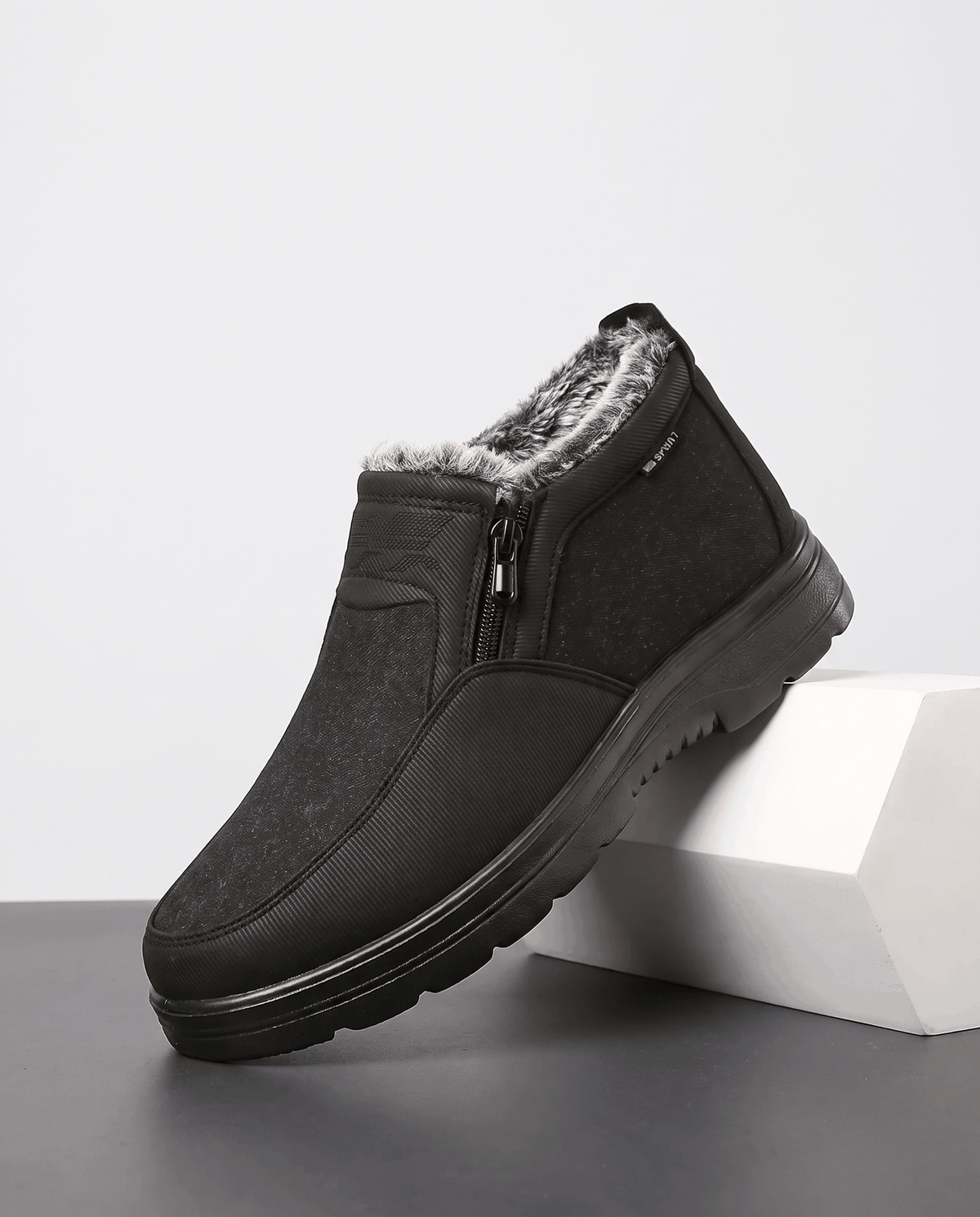 Black fleece-lined ankle boot shown on a white pedestal.