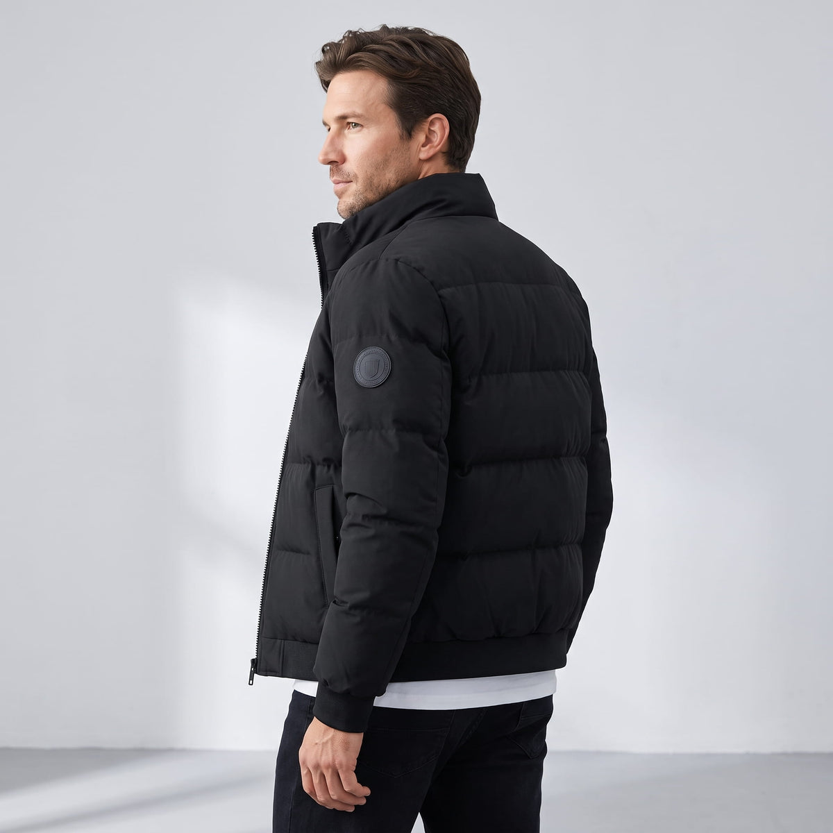 Rear three-quarter view in black showing the sleeve patch and boxy quilting
