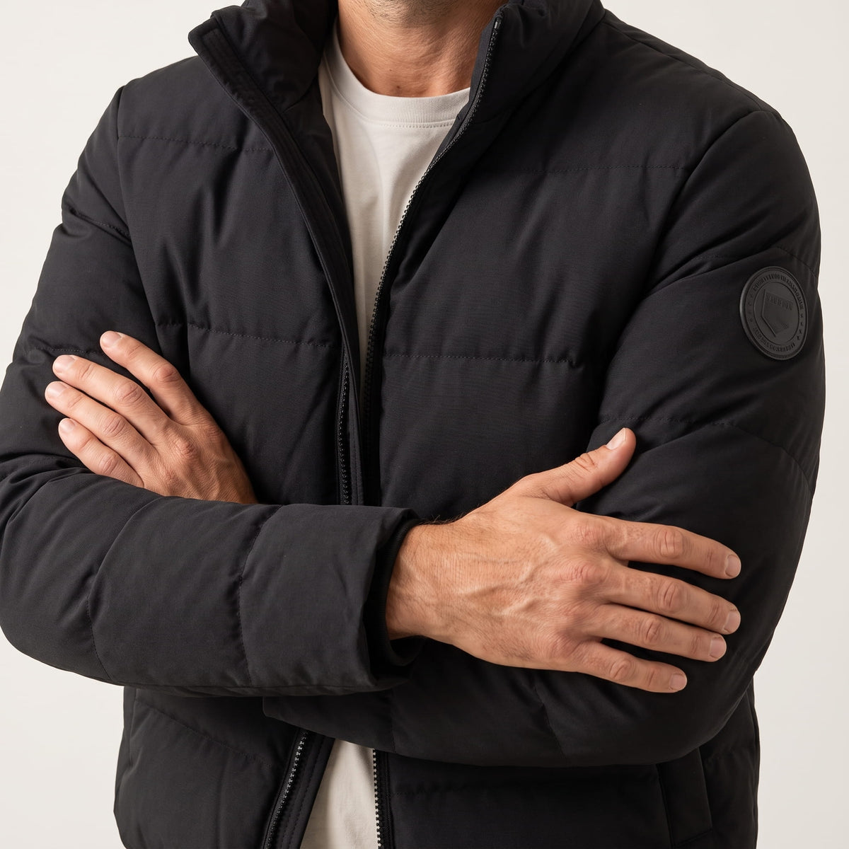 Black jacket with arms crossed, quilted chest panels and contrast ribbed cuffs