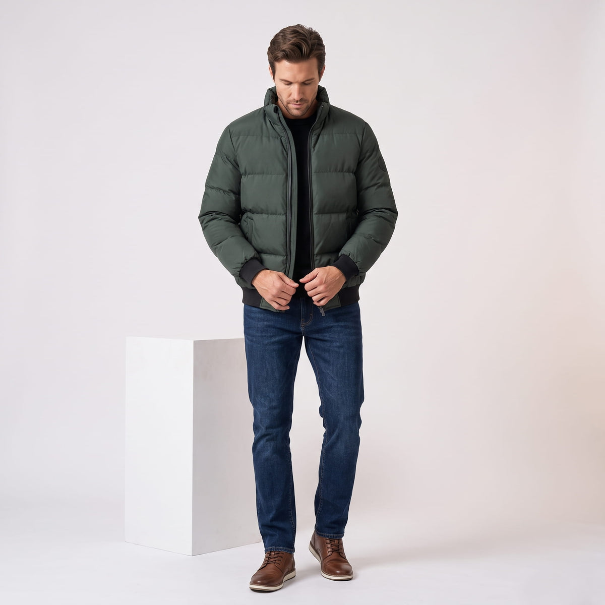 Dark green jacket styled with blue jeans and brown boots, adjusting the zip