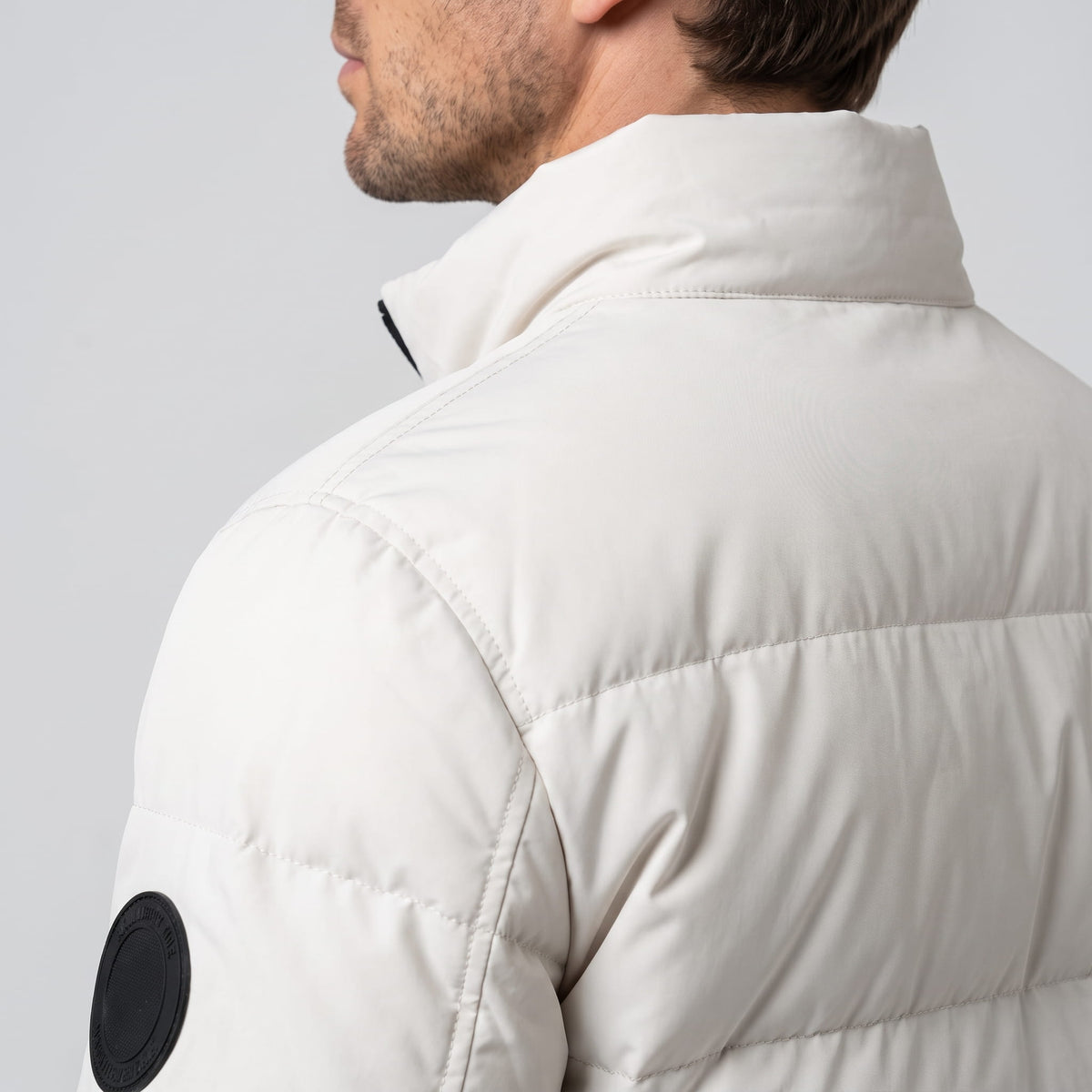 White jacket shoulder detail with the raised collar and circular sleeve patch