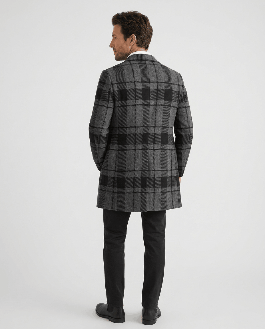 Back view of the black and gray plaid overcoat worn with dark trousers