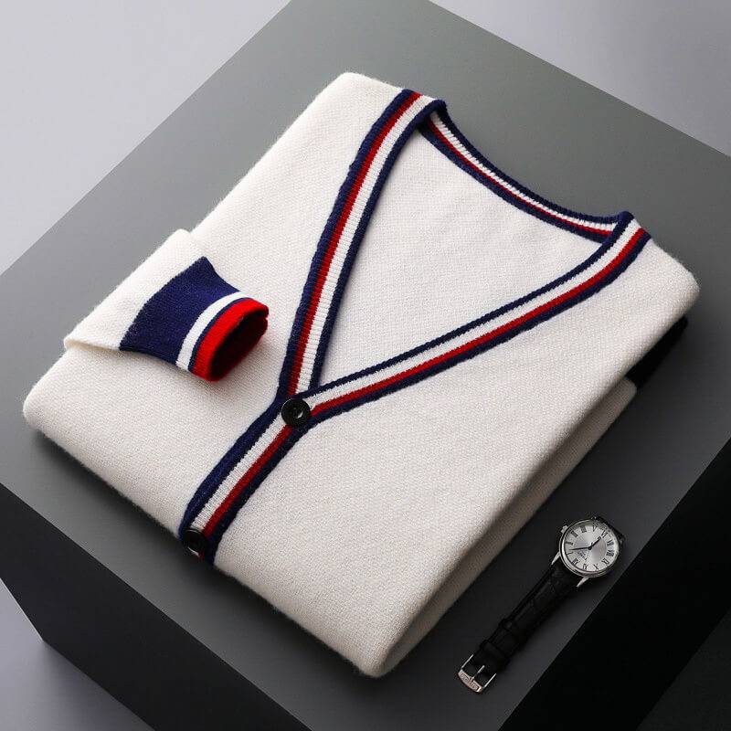 Cream white striped-trim cardigan folded flat beside a wristwatch on a dark surface