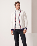 Front view of the cream white cardigan open over a white turtleneck with striped cuffs