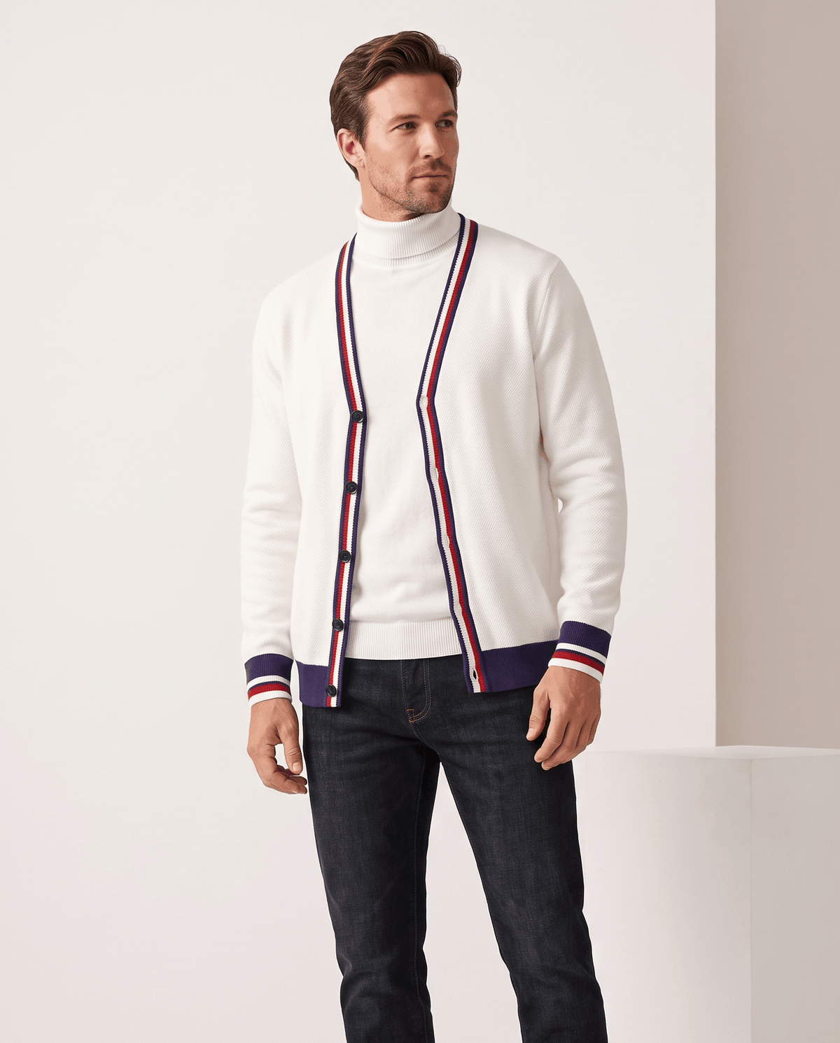 Front view of the cream white cardigan open over a white turtleneck with striped cuffs