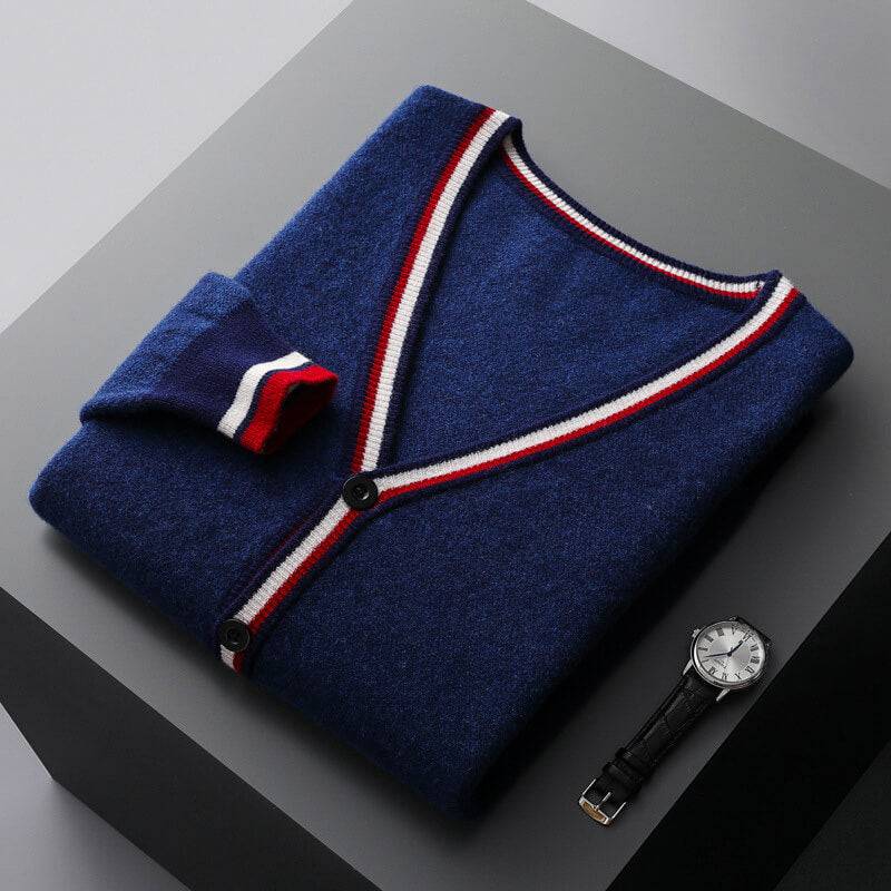 Dark blue cardigan with red and white striped trim folded flat beside a watch