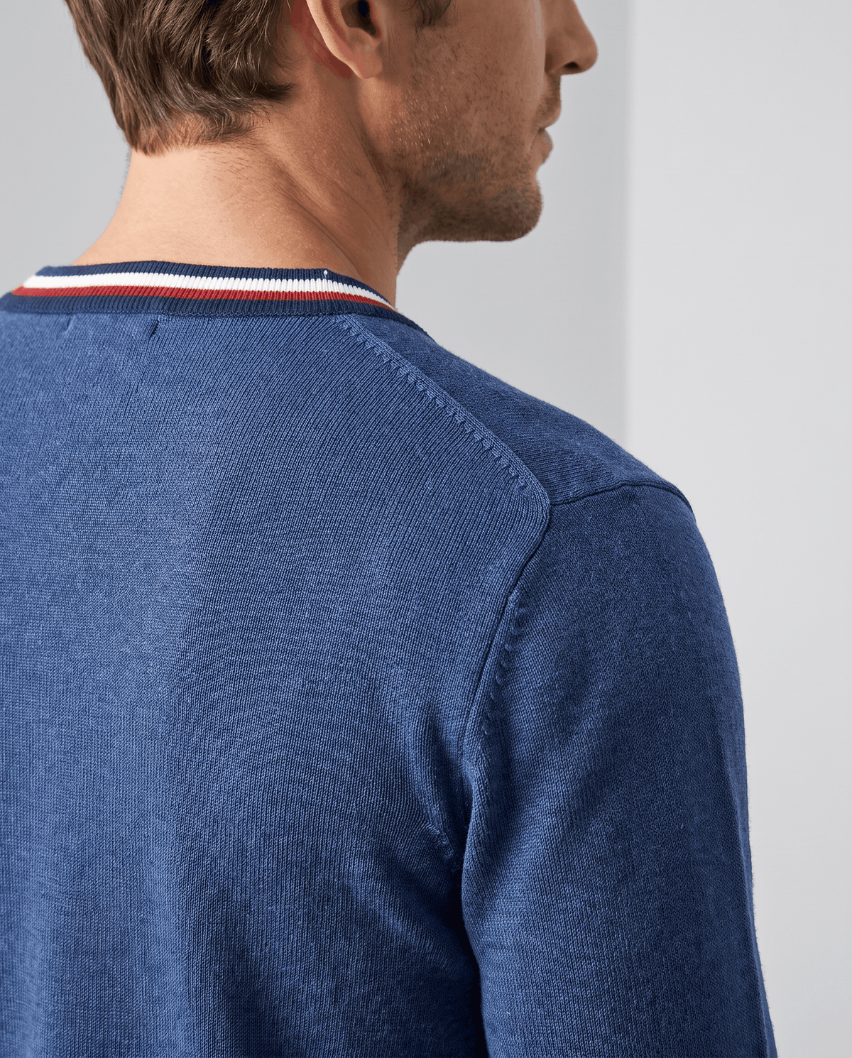 Side profile close-up of the deep blue knit and striped neckline trim
