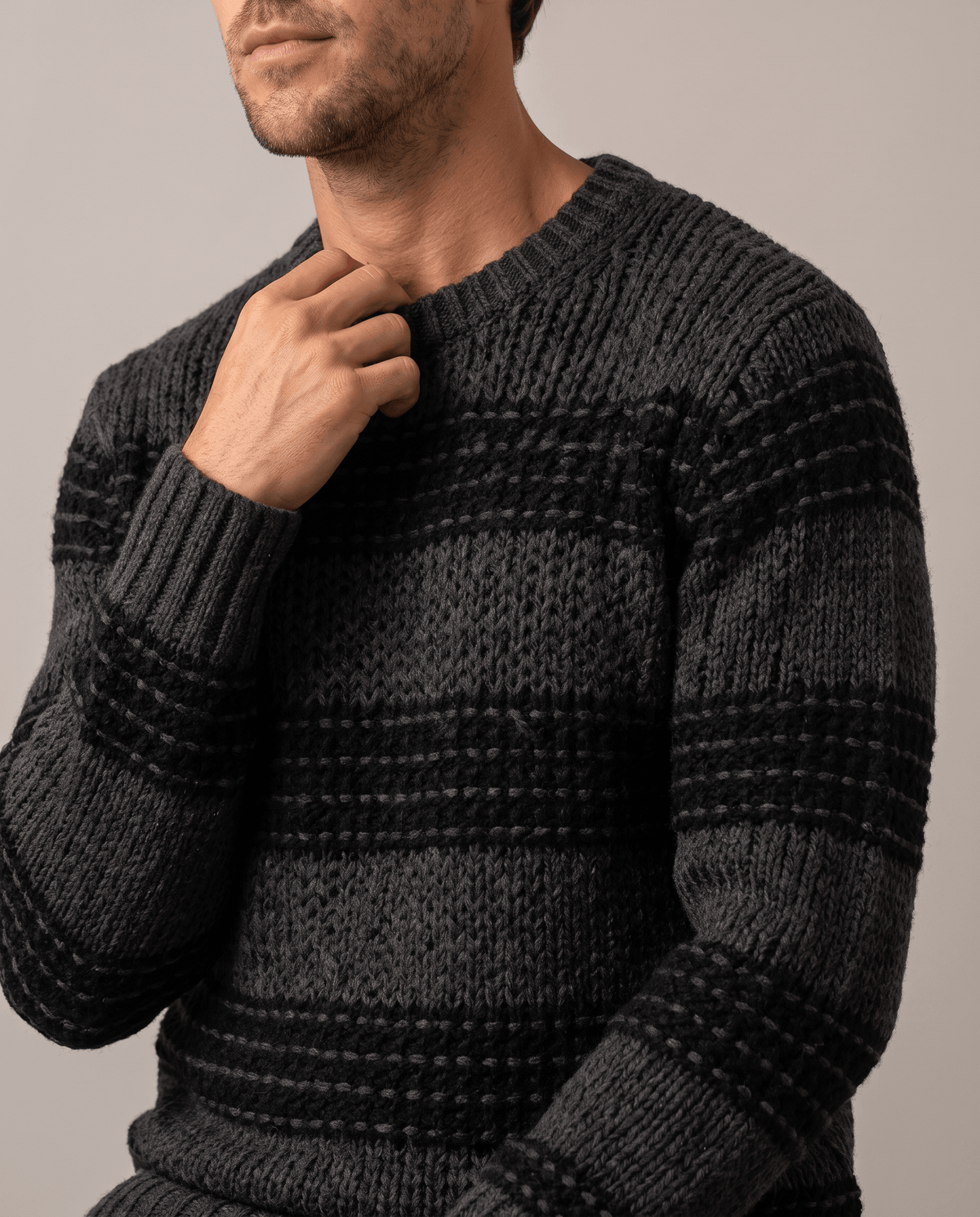 Close-up of hand at the ribbed collar of a black striped knit