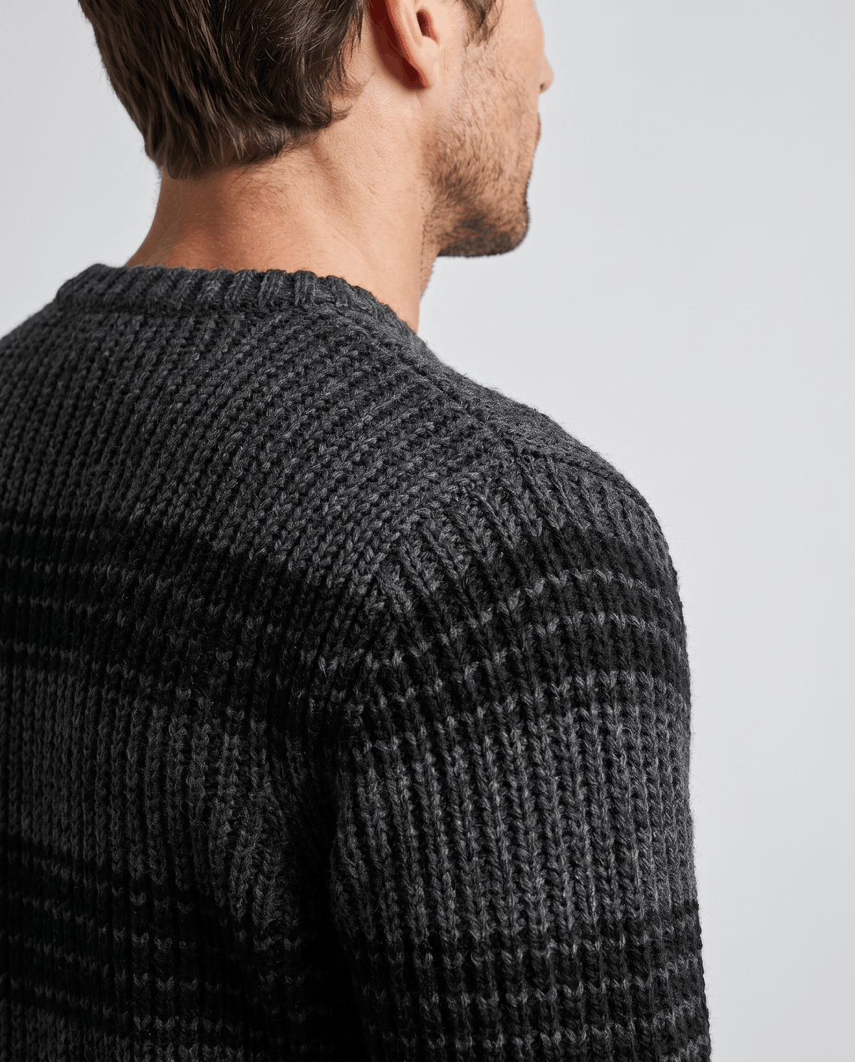 Side close-up of black striped sweater collar and marled shoulder