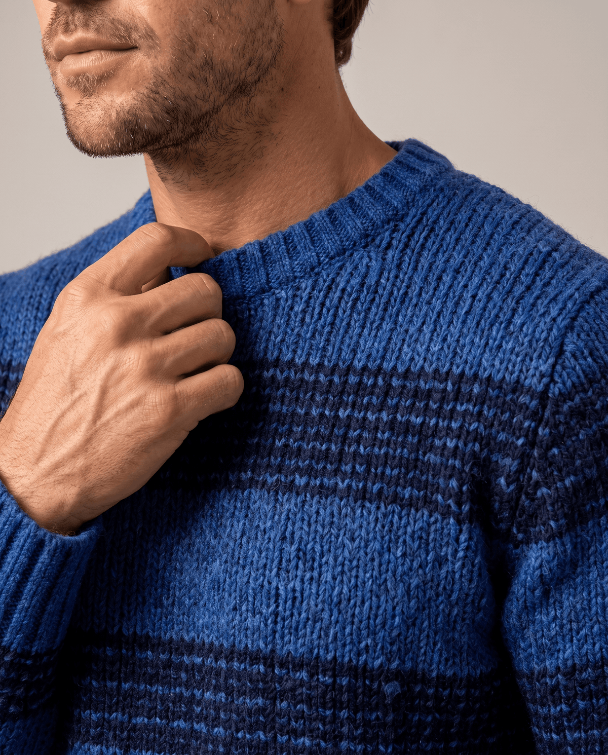 Close-up of hand at the ribbed collar of a blue striped knit