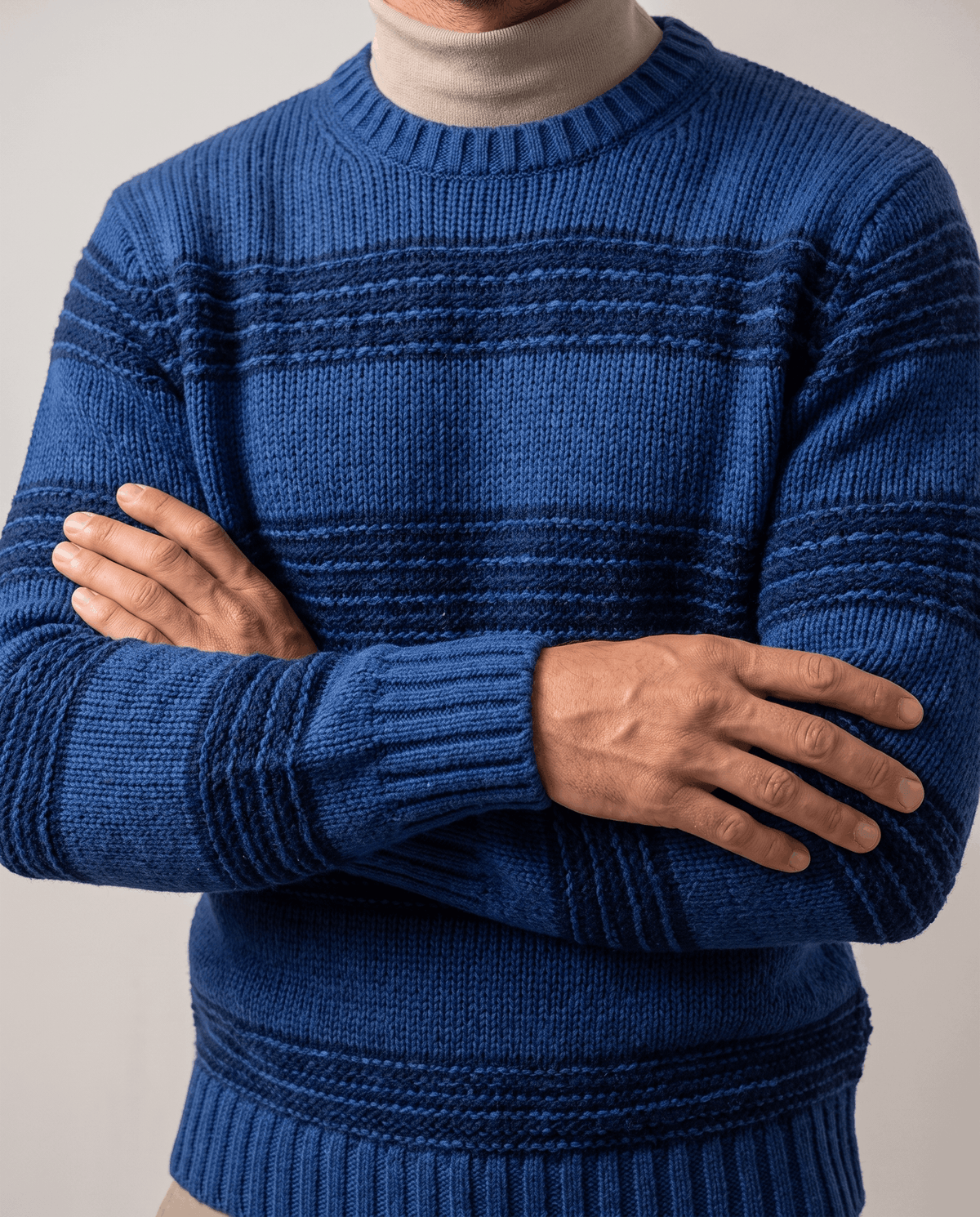 Blue striped knit over beige mock neck with arm folded across chest